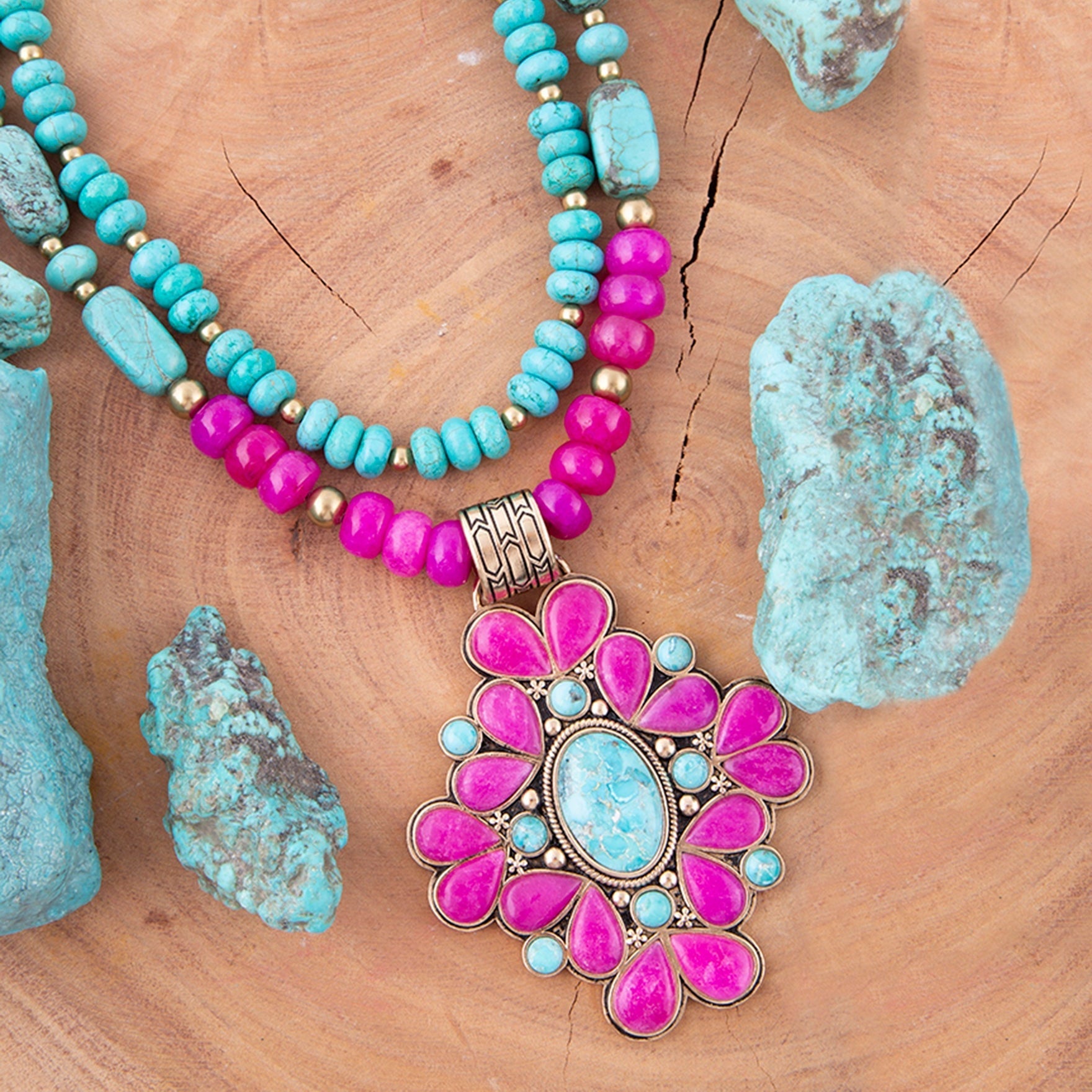 Necklace with pink and turquoise beads and pendant on a wooden surface with turquoise stones.