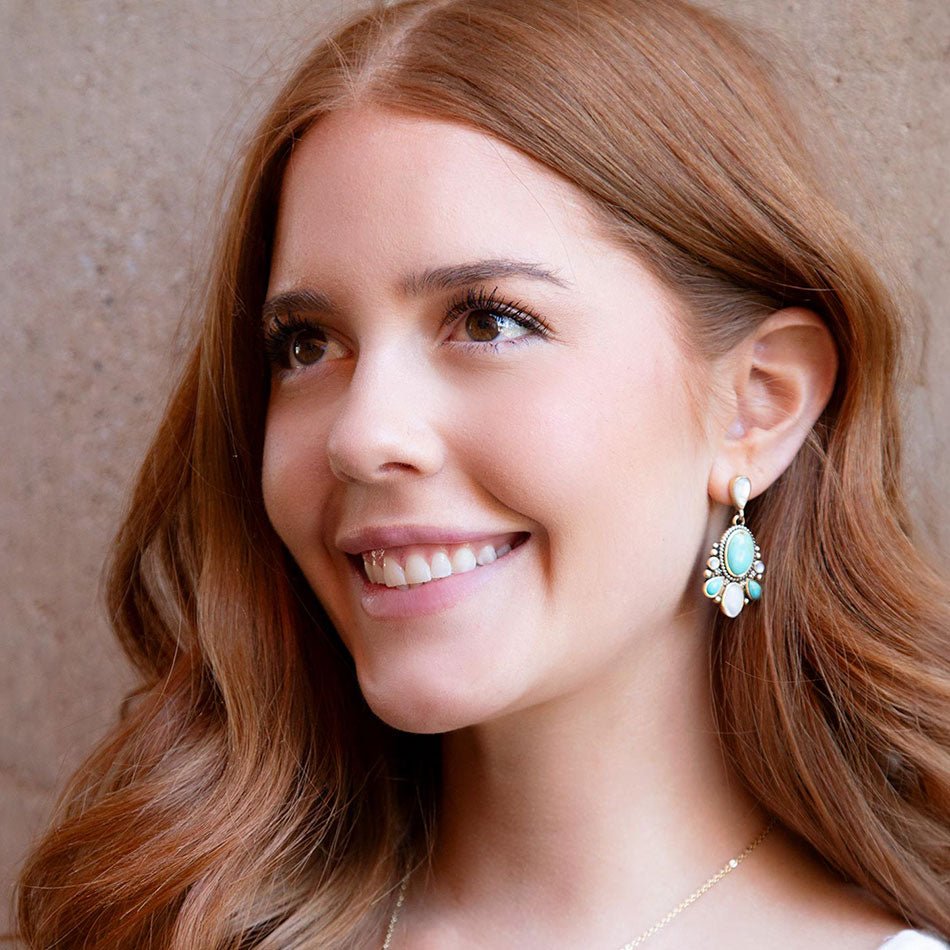 Woman wearing turquoise earrings with a neutral background