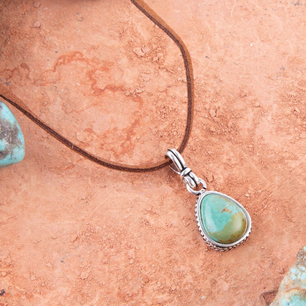 Turquoise pendant on a cord with a natural stone background