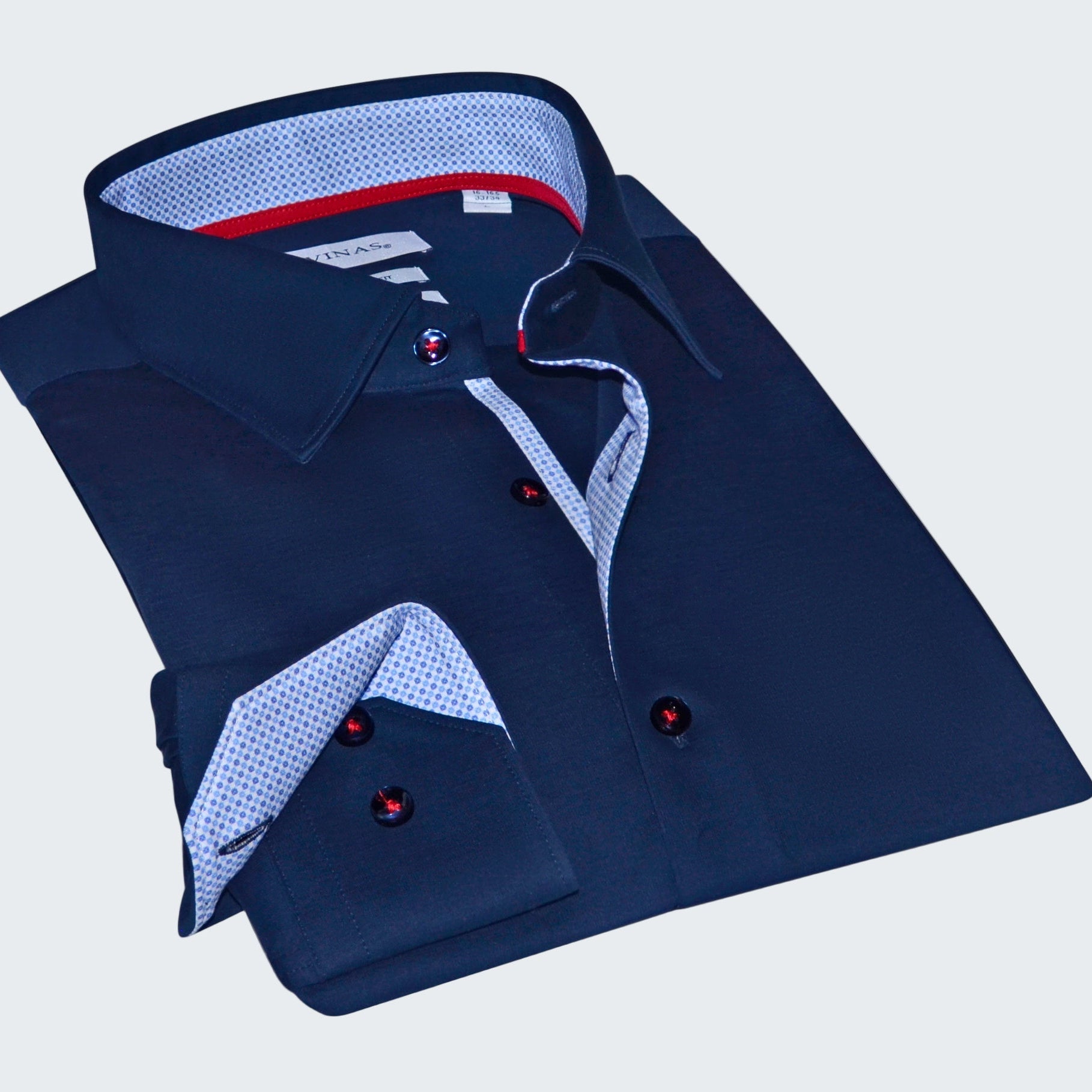 Folded navy blue dress shirt with patterned trim on a white background