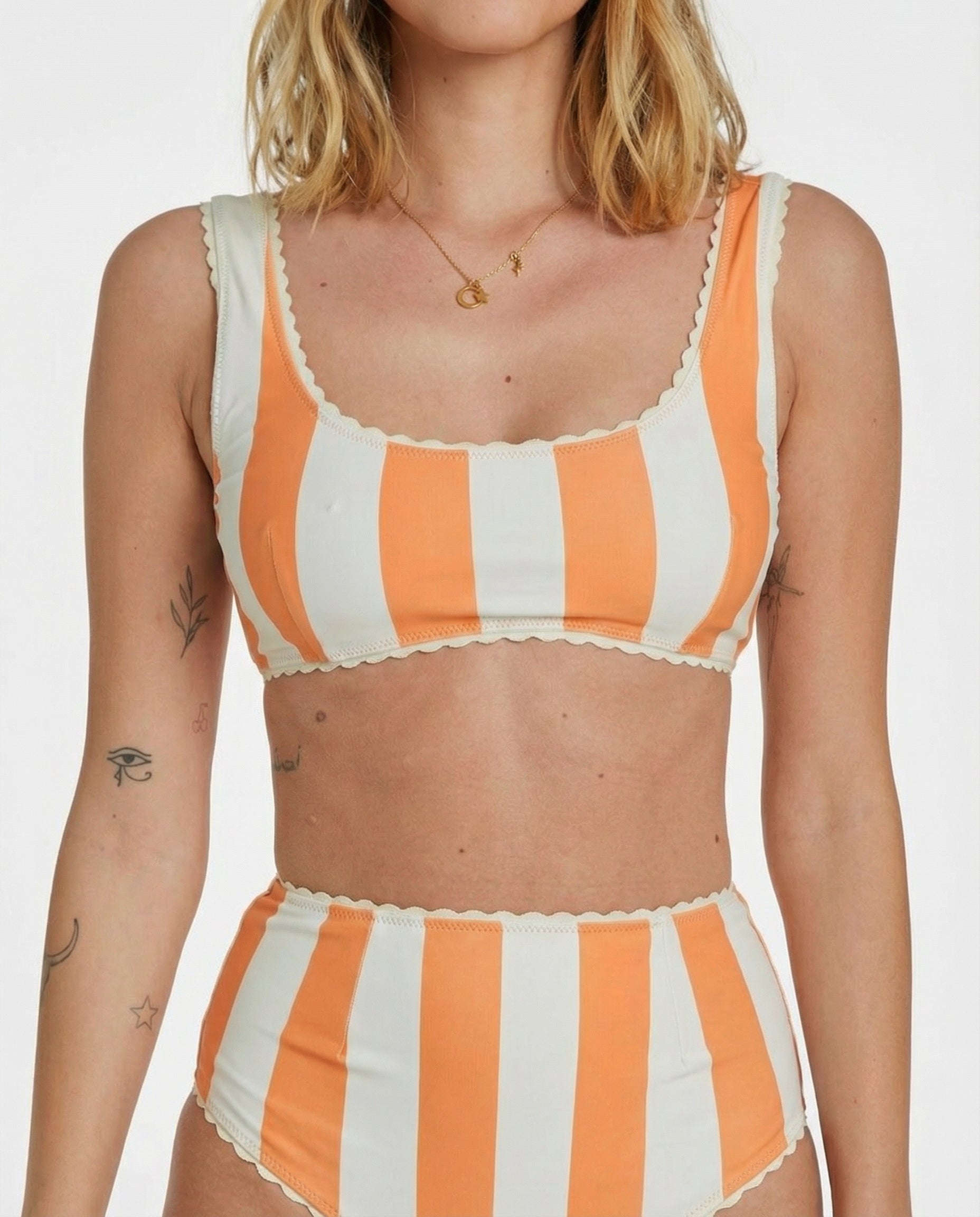 Woman wearing an orange and white striped bikini set on a plain background