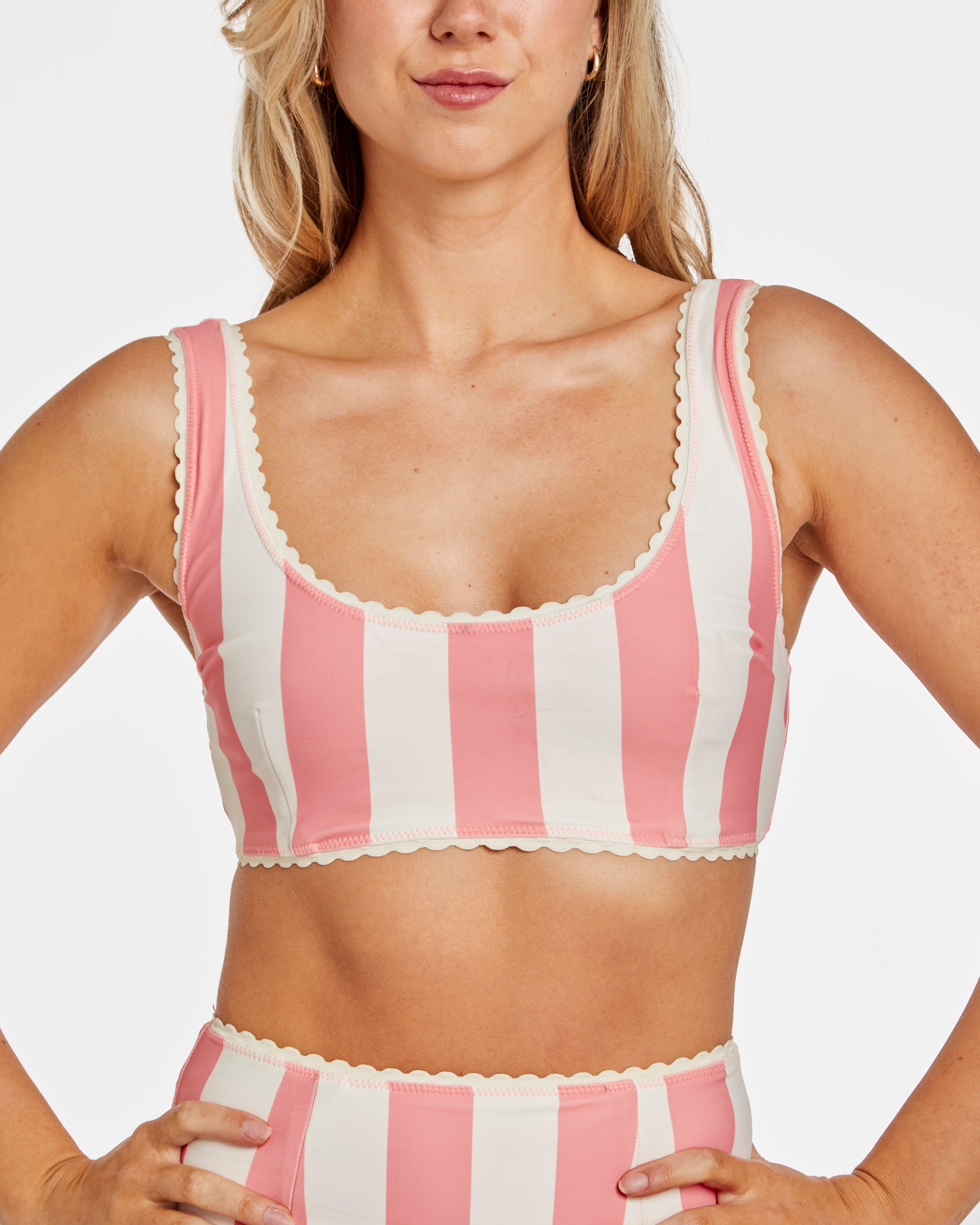 Woman wearing a pink and white striped bikini top with a plain background