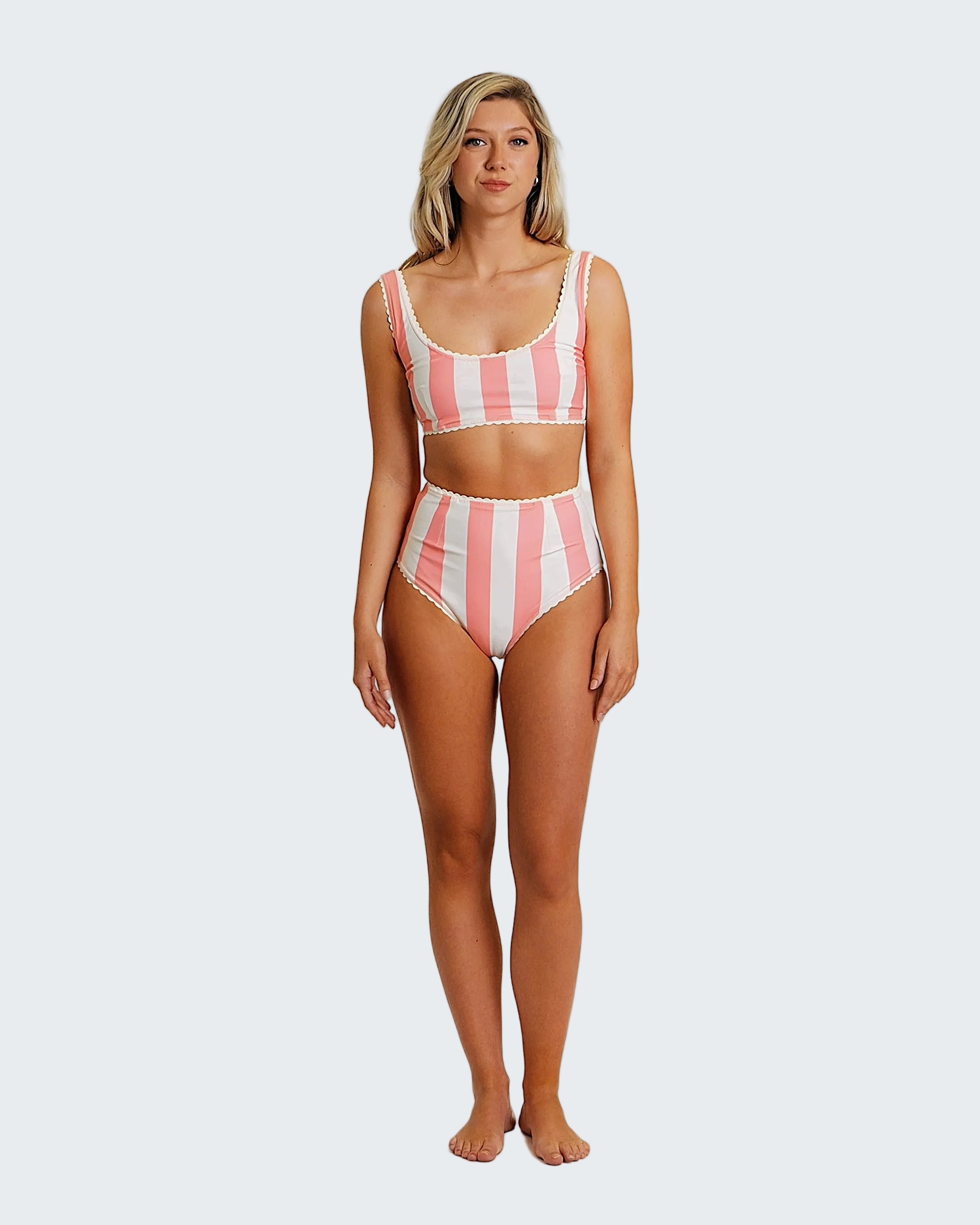 Woman wearing a pink and white striped swimsuit on a white background