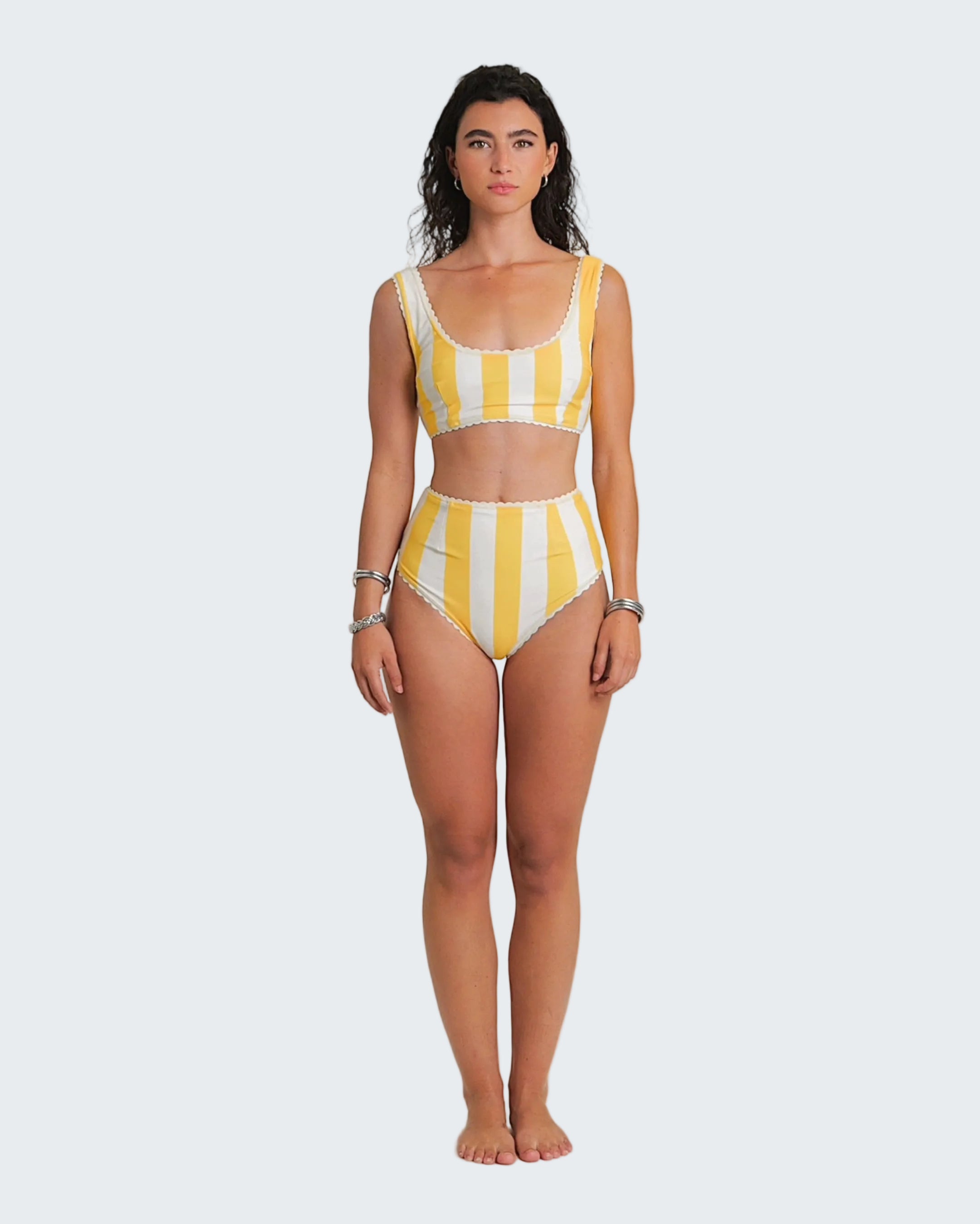 Woman wearing a yellow and white striped swimsuit on a white background