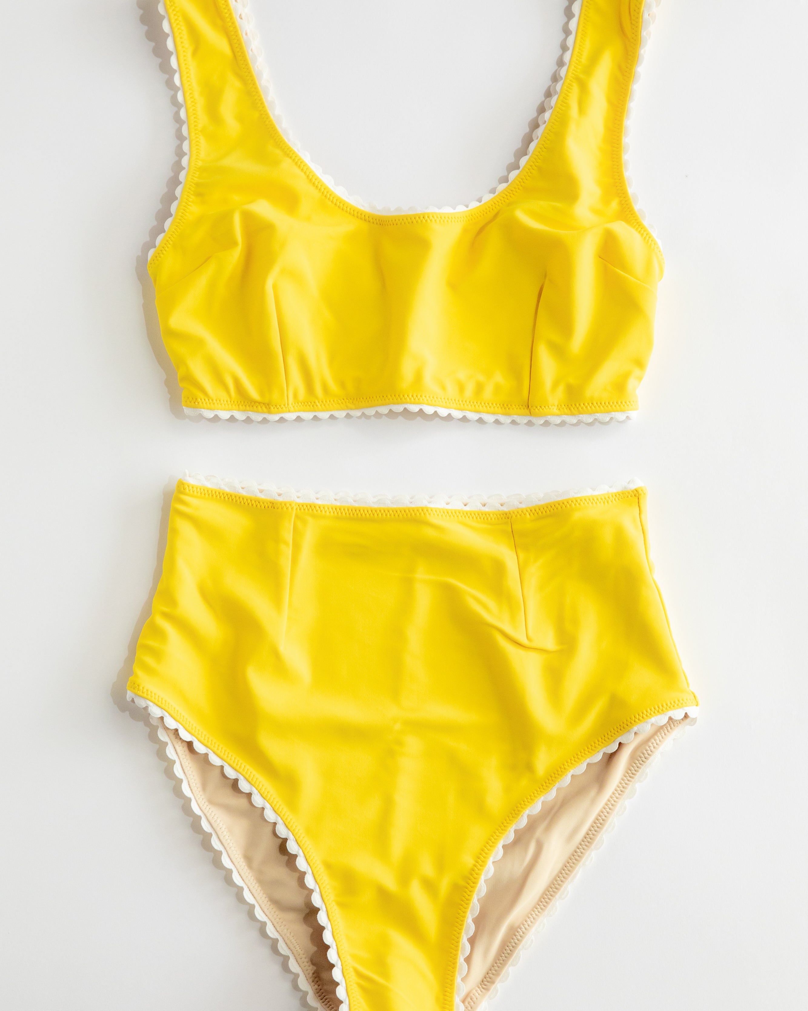 Yellow swimsuit with lace trim on a white background