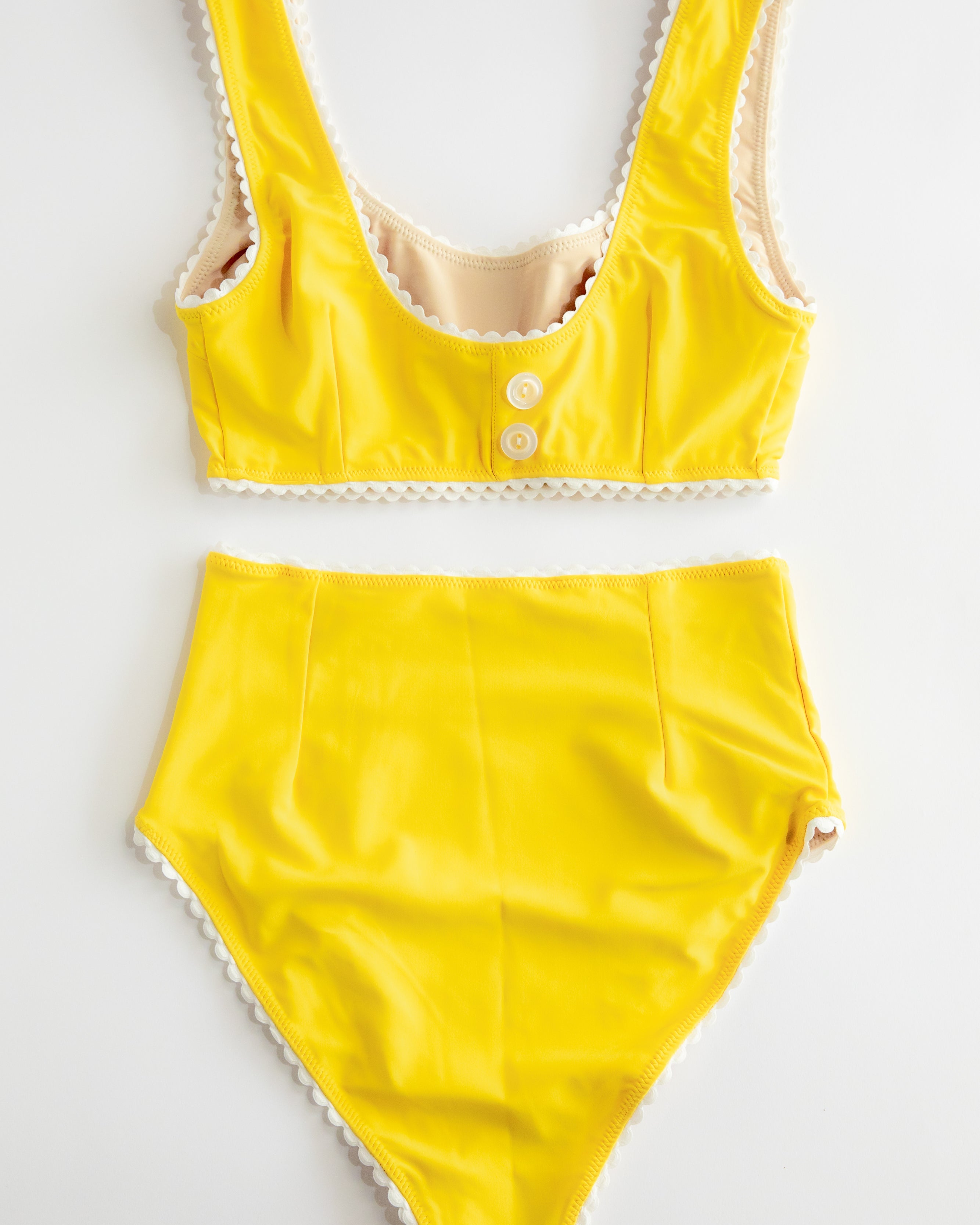 Yellow swimsuit with lace details on a white background