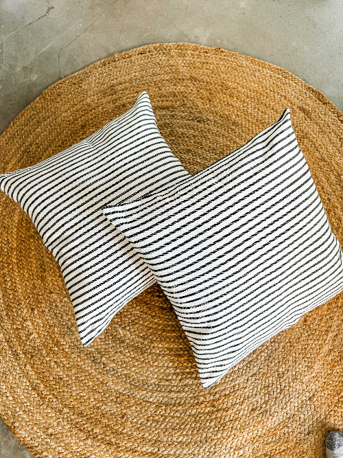 Two striped pillows on a woven mat