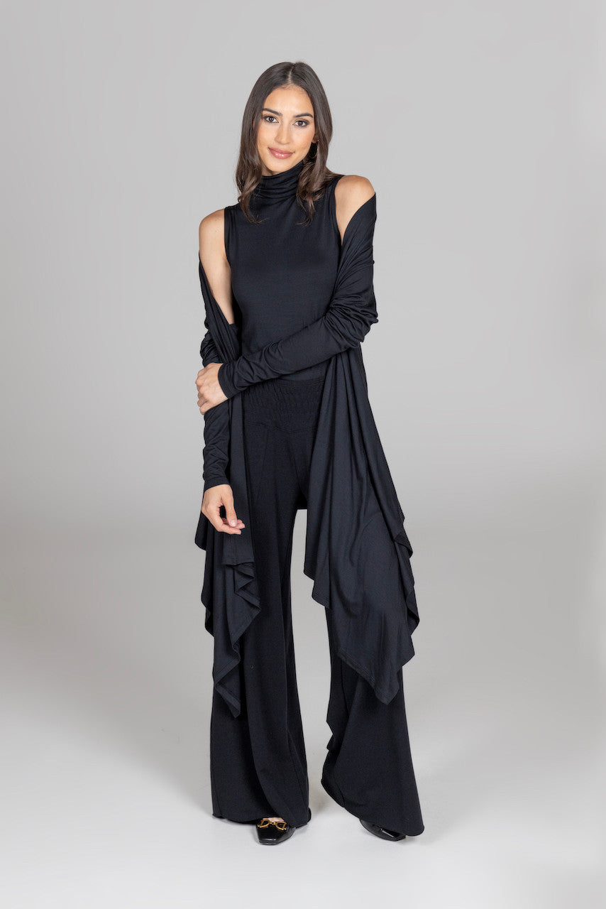 Woman wearing a black outfit with ruffled details on a gray background
