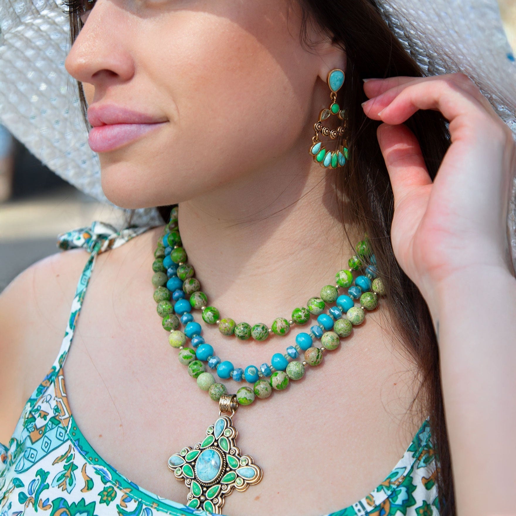 Woman wearing green and blue beaded jewelry with a blurred background