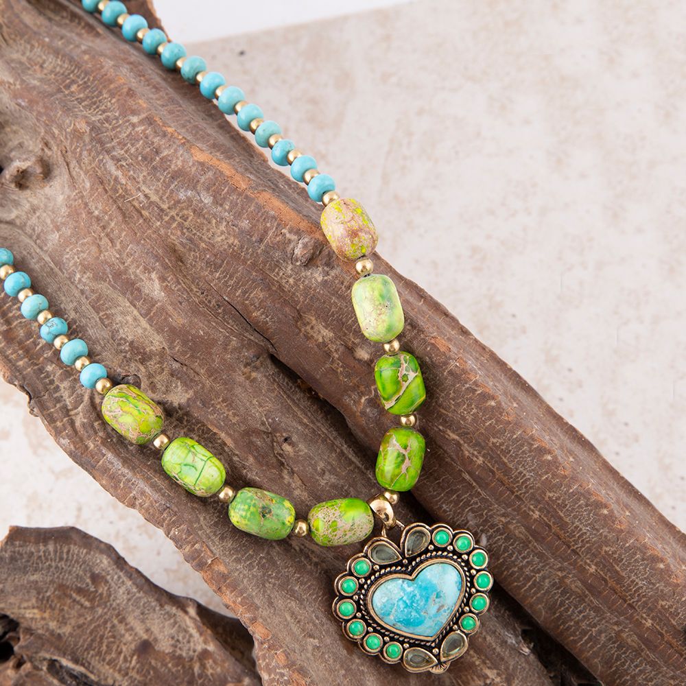 Necklace with green and turquoise beads and a heart-shaped pendant on wooden background