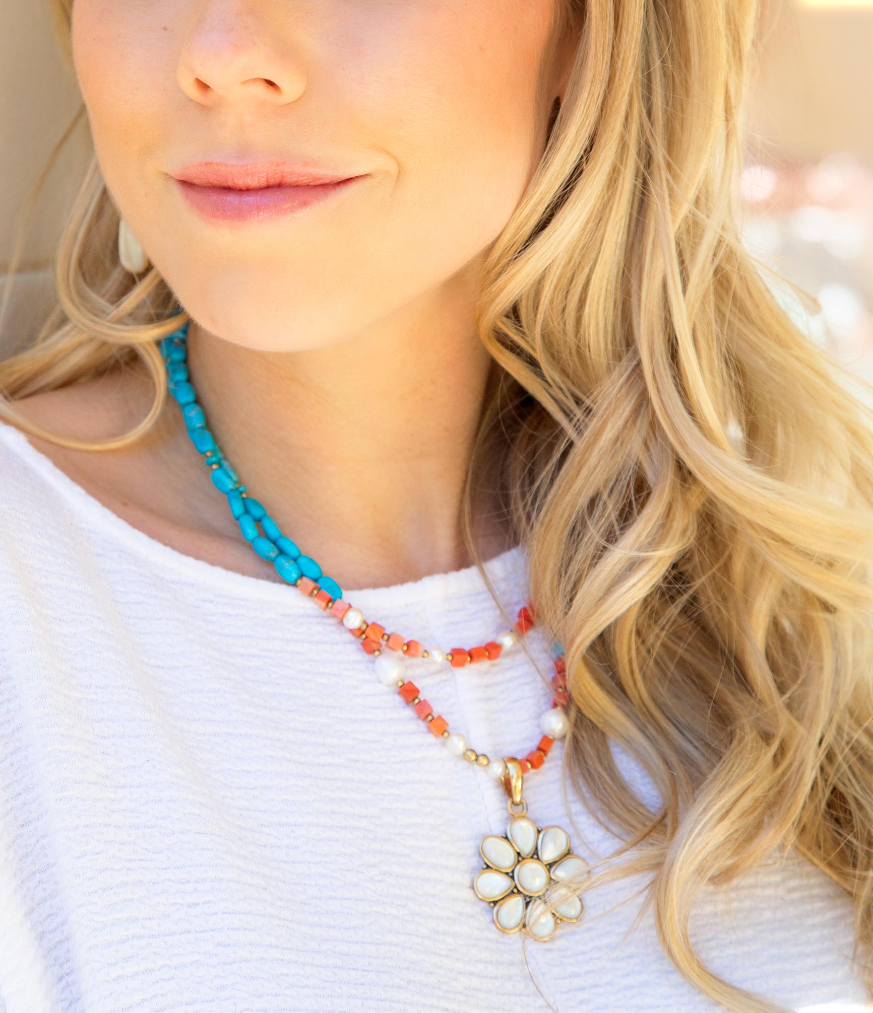 Close-up of a woman wearing a colorful beaded necklace with a floral pendant.