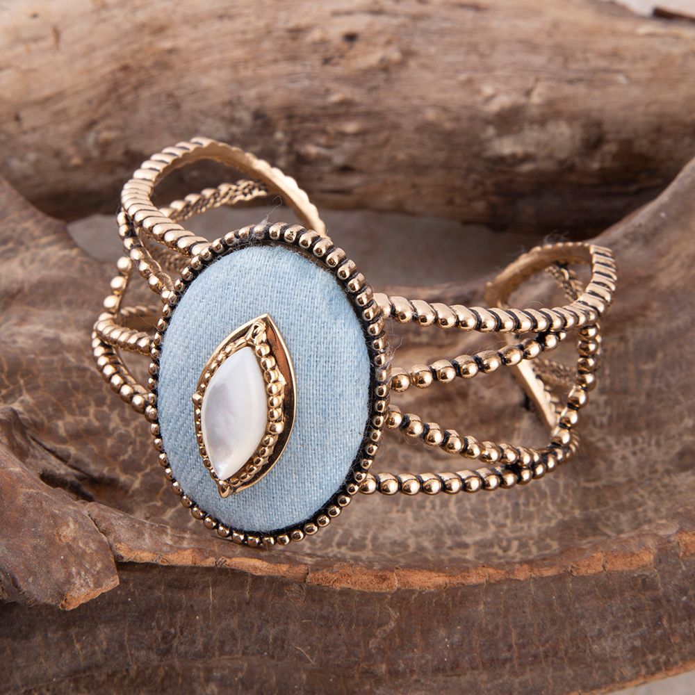 Gold bracelet with a blue stone on a wooden surface