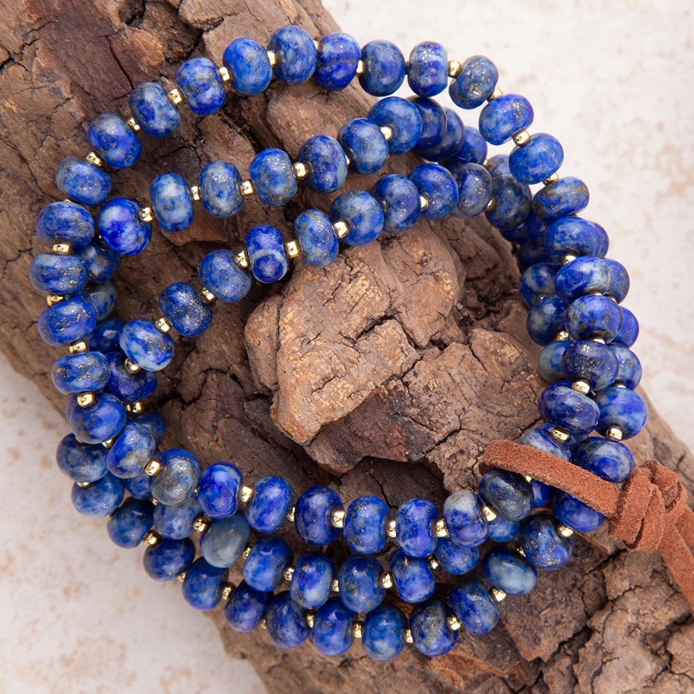 Blue beaded bracelet with a brown leather strap on a textured surface