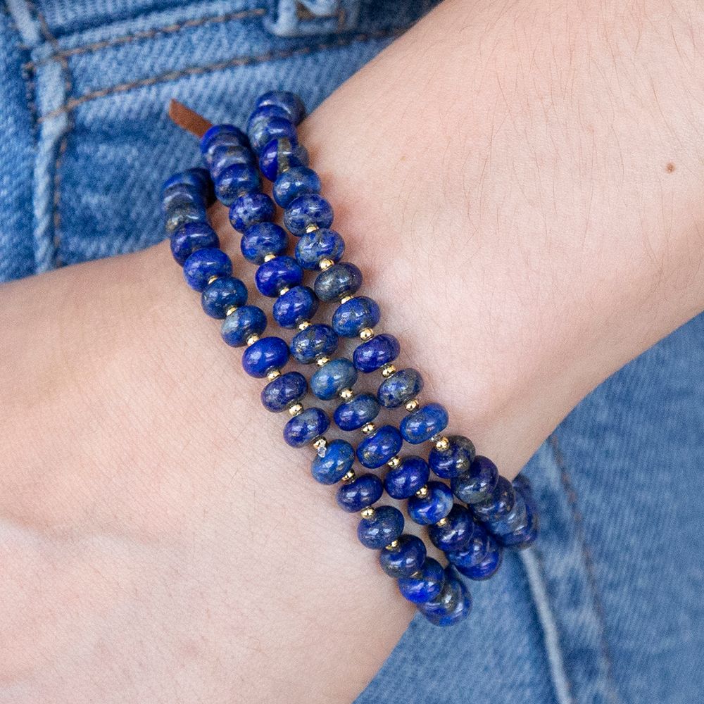Blue beaded bracelet on a wrist with denim background