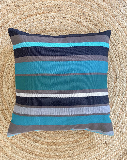 Striped pillow with blue and gray colors on a woven mat background