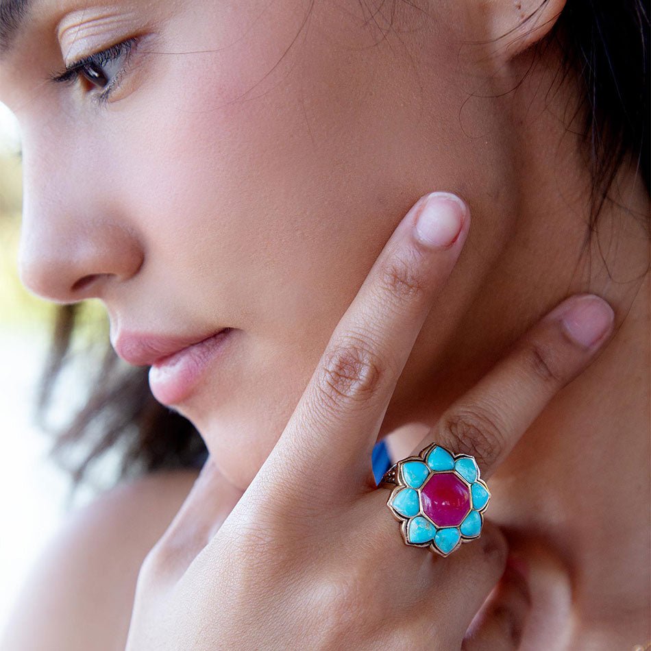 Close-up of a woman wearing a colorful floral ring with a pink gemstone.