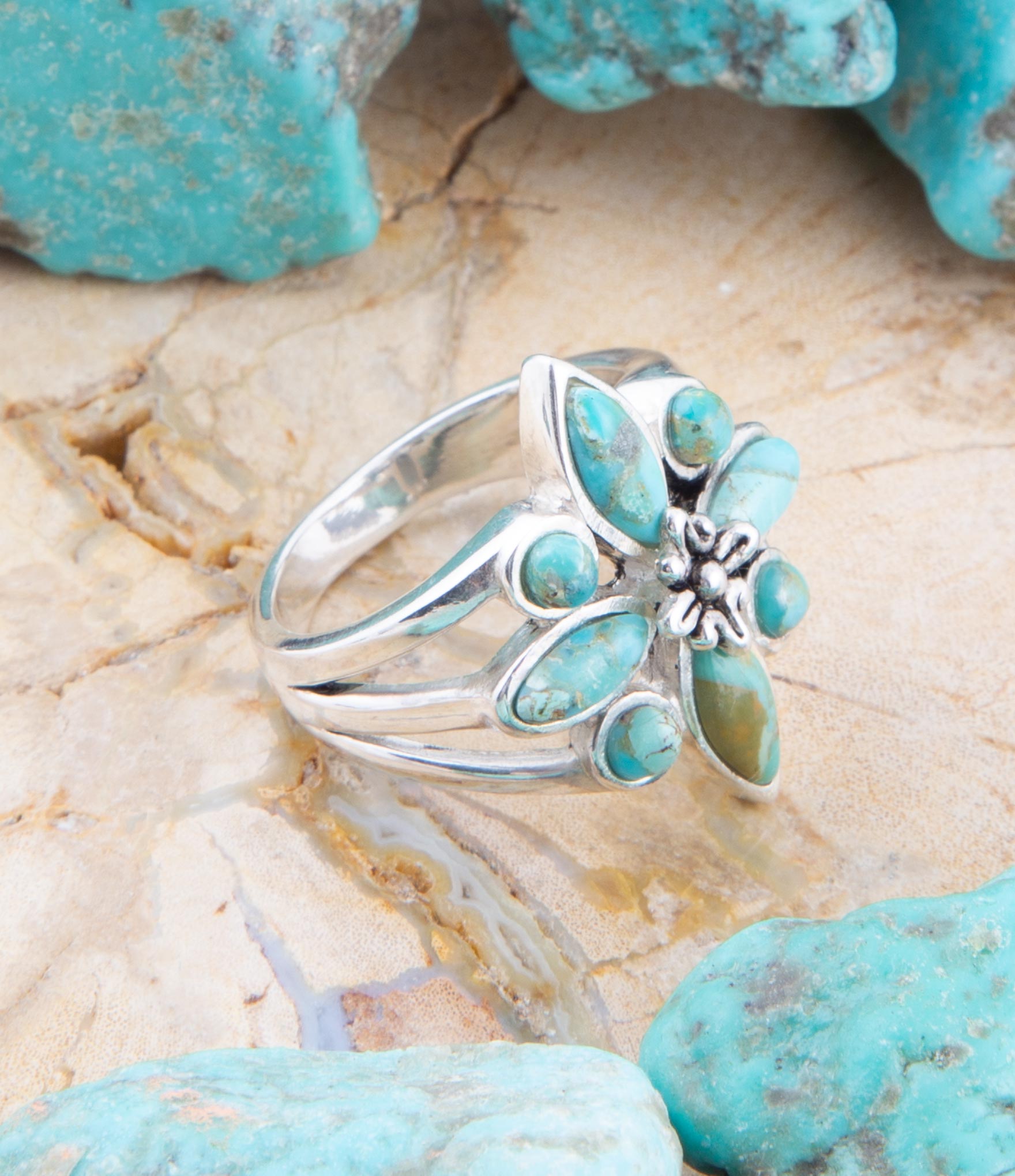 Silver ring with turquoise stones on a stone surface