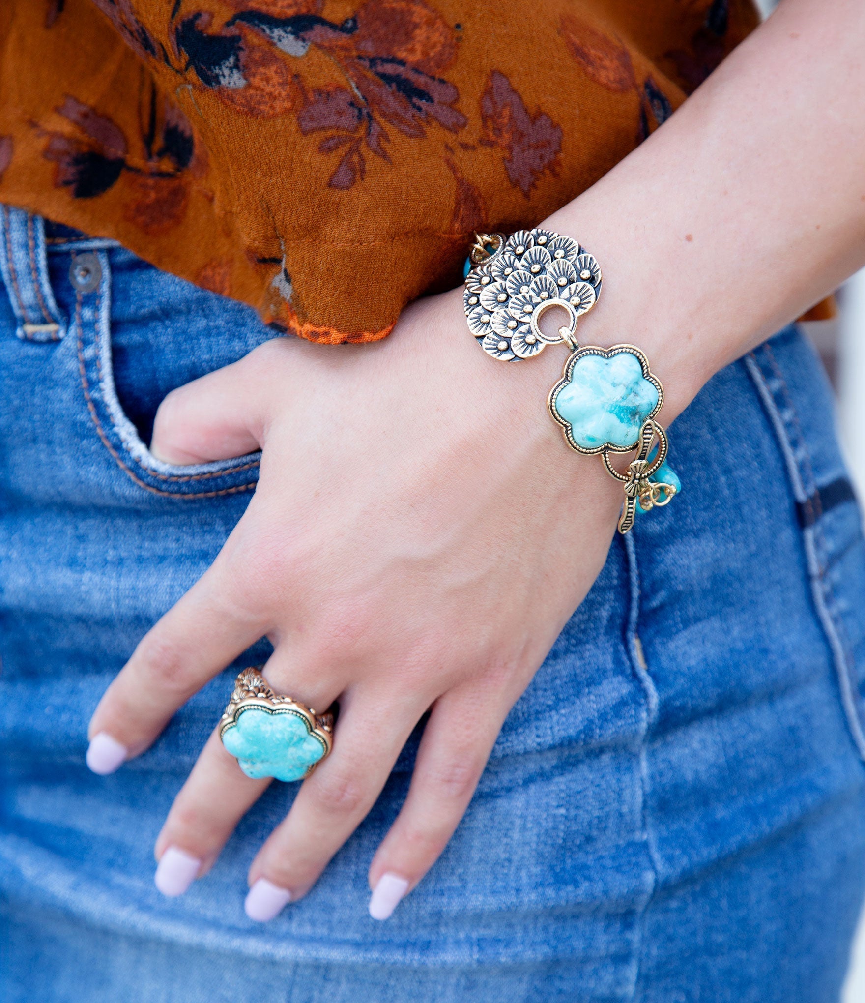 Close-up of a hand wearing a turquoise ring and bracelet on a blurred background