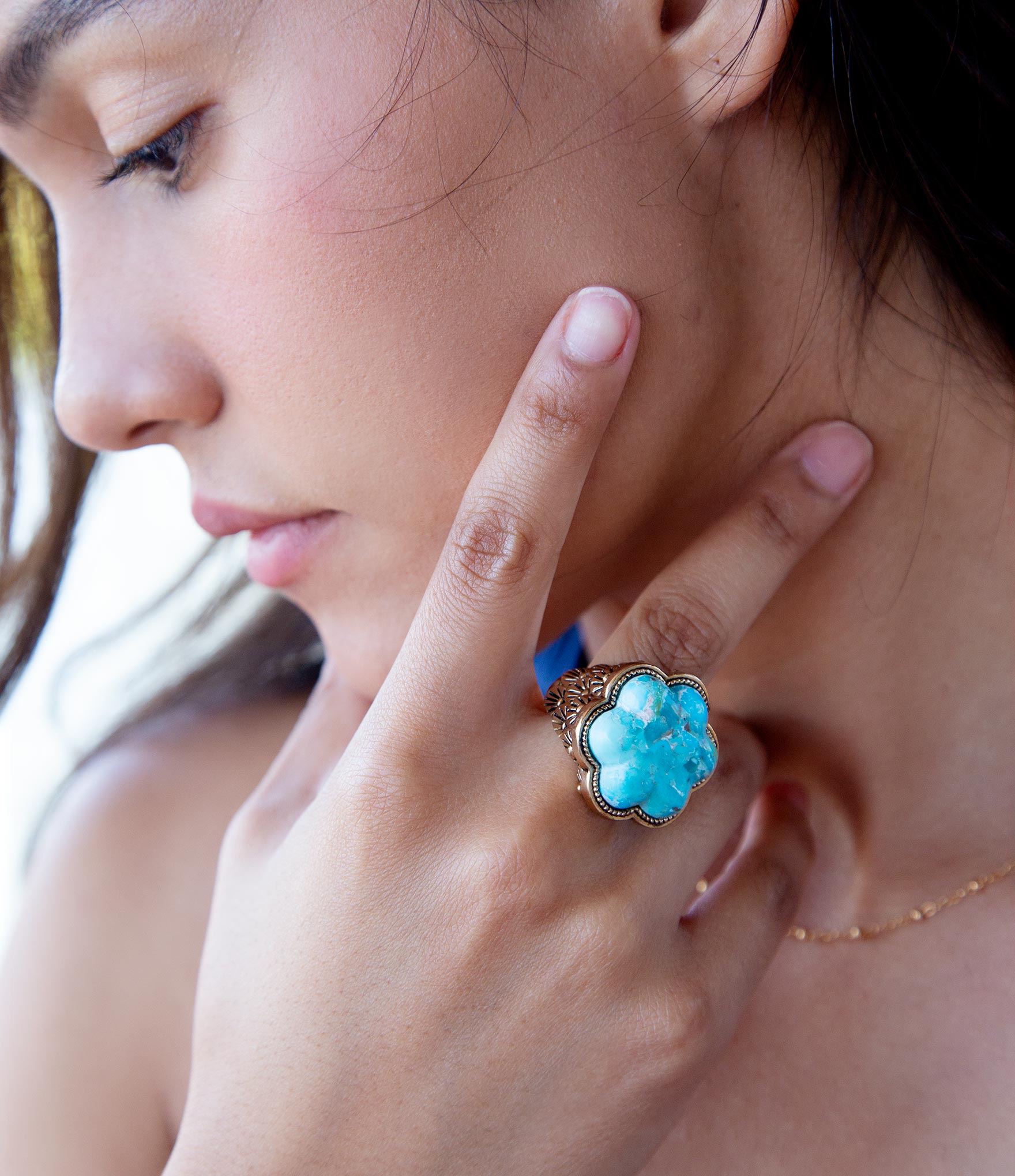 Close-up of a woman wearing a turquoise floral ring.