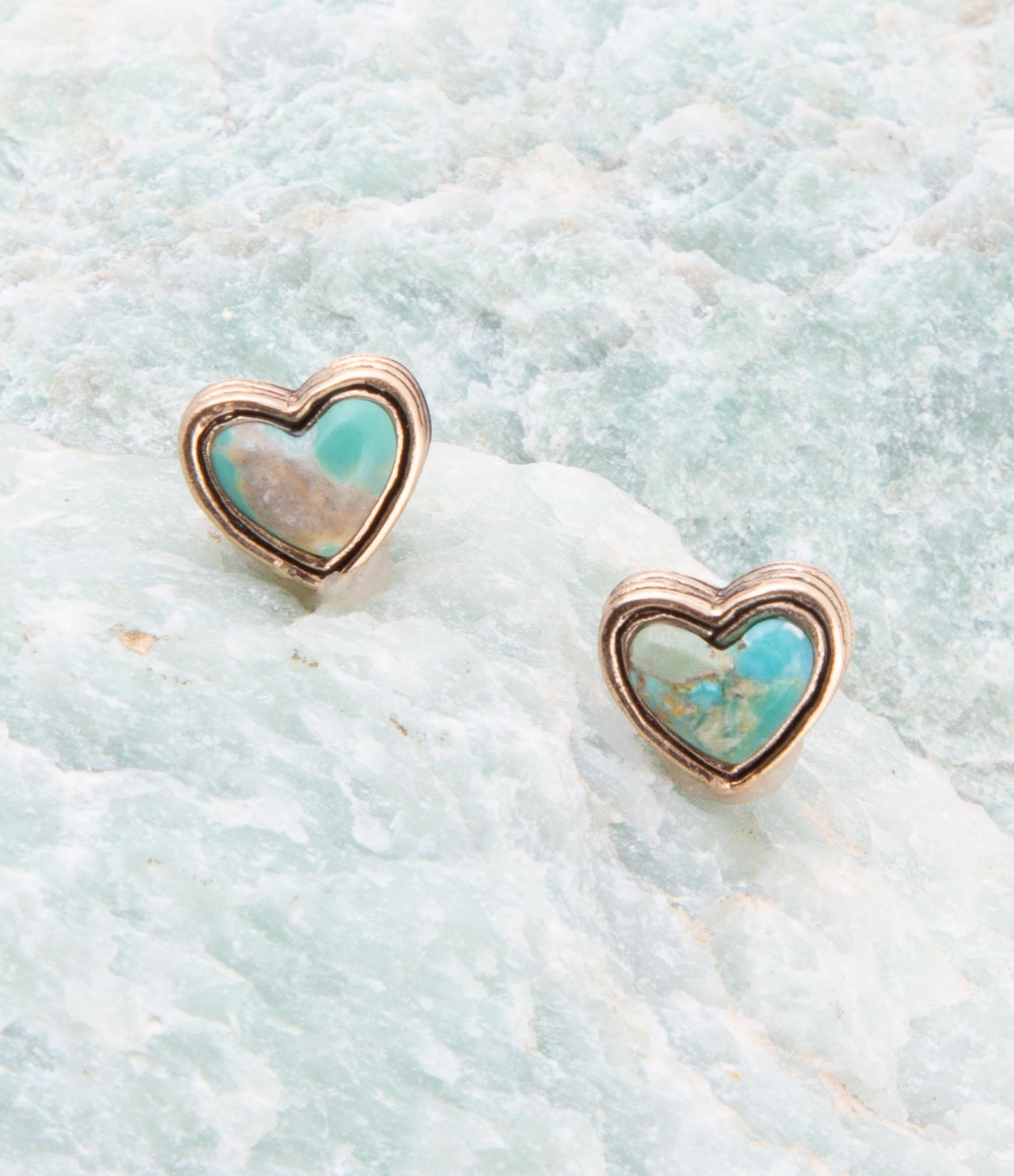 Heart-shaped earrings with turquoise centers on a light blue textured background