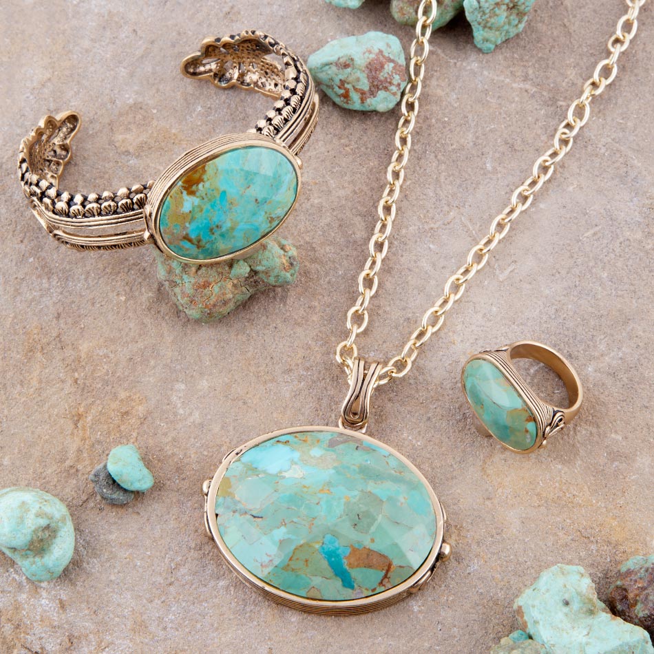 Turquoise stone jewelry set with necklace, bracelet, and ring on a stone surface.