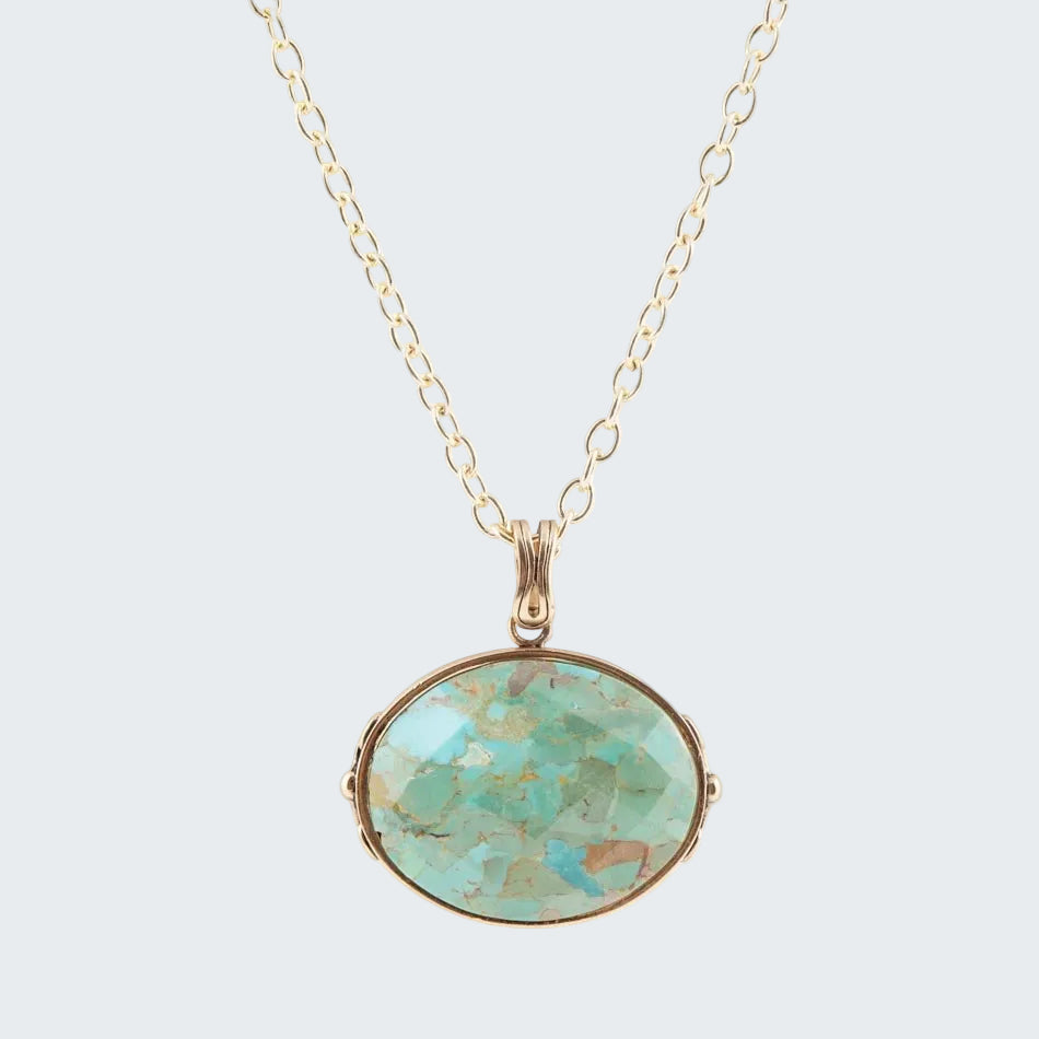 Turquoise pendant necklace on a gold chain against a white background