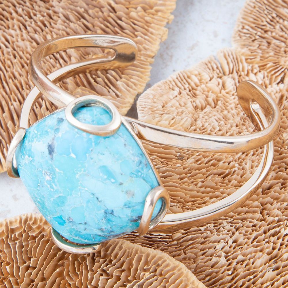 Silver ring with a turquoise stone on a textured beige surface