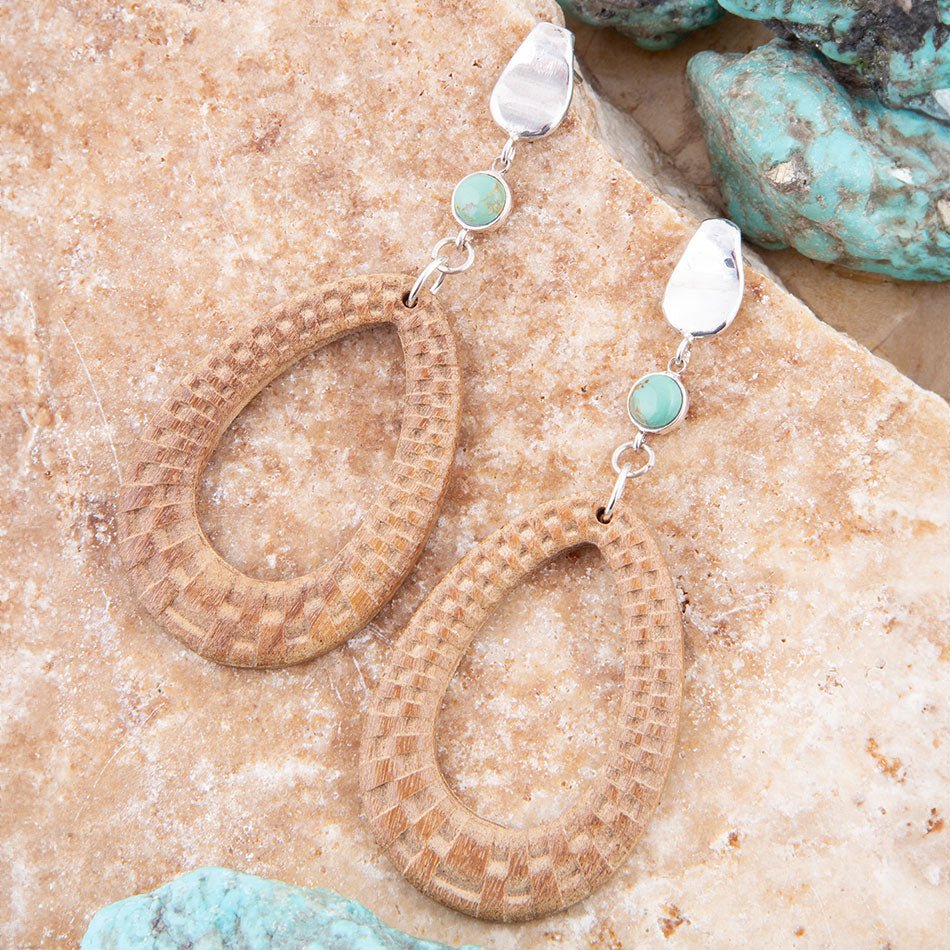 Pair of earrings with turquoise stones on a stone surface