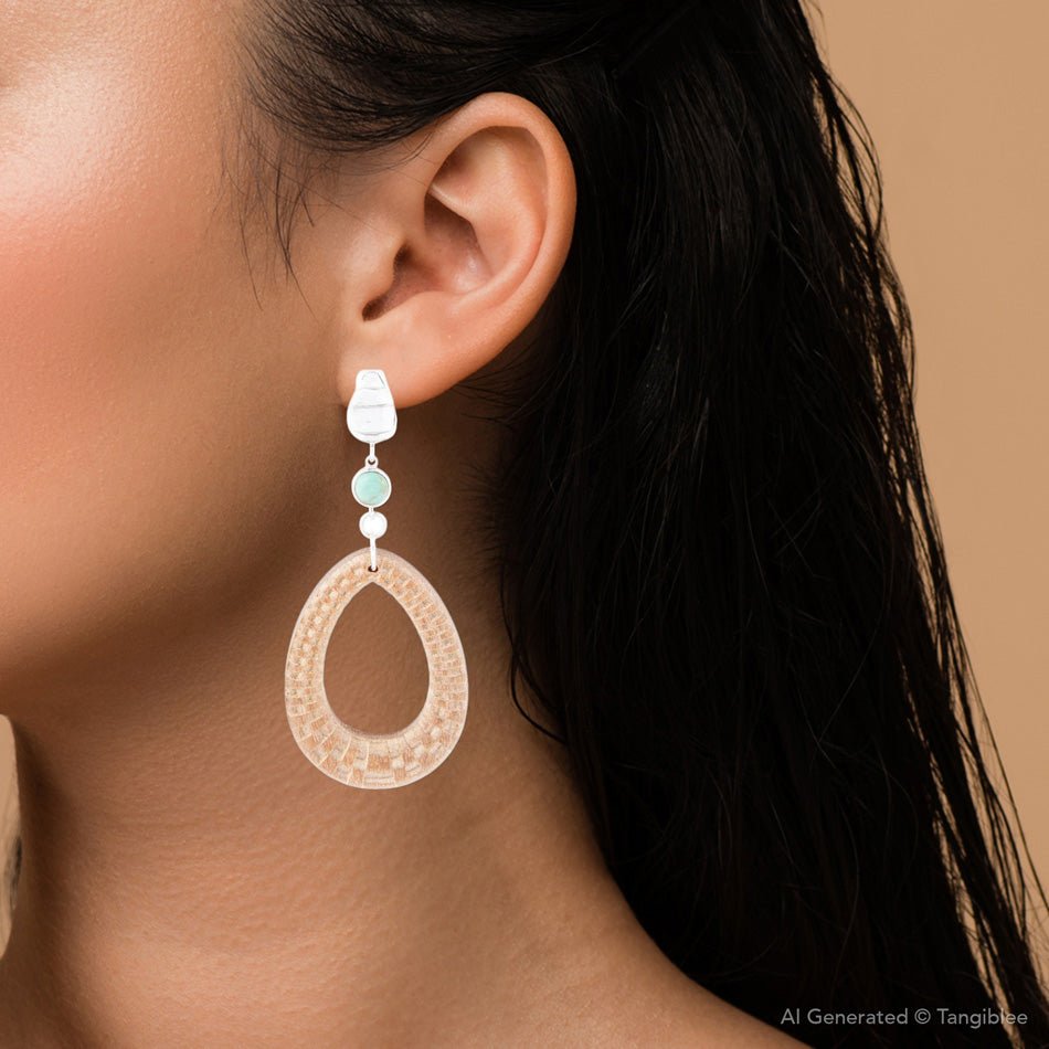 Close-up of a woman wearing a decorative earring with a beige and turquoise design.