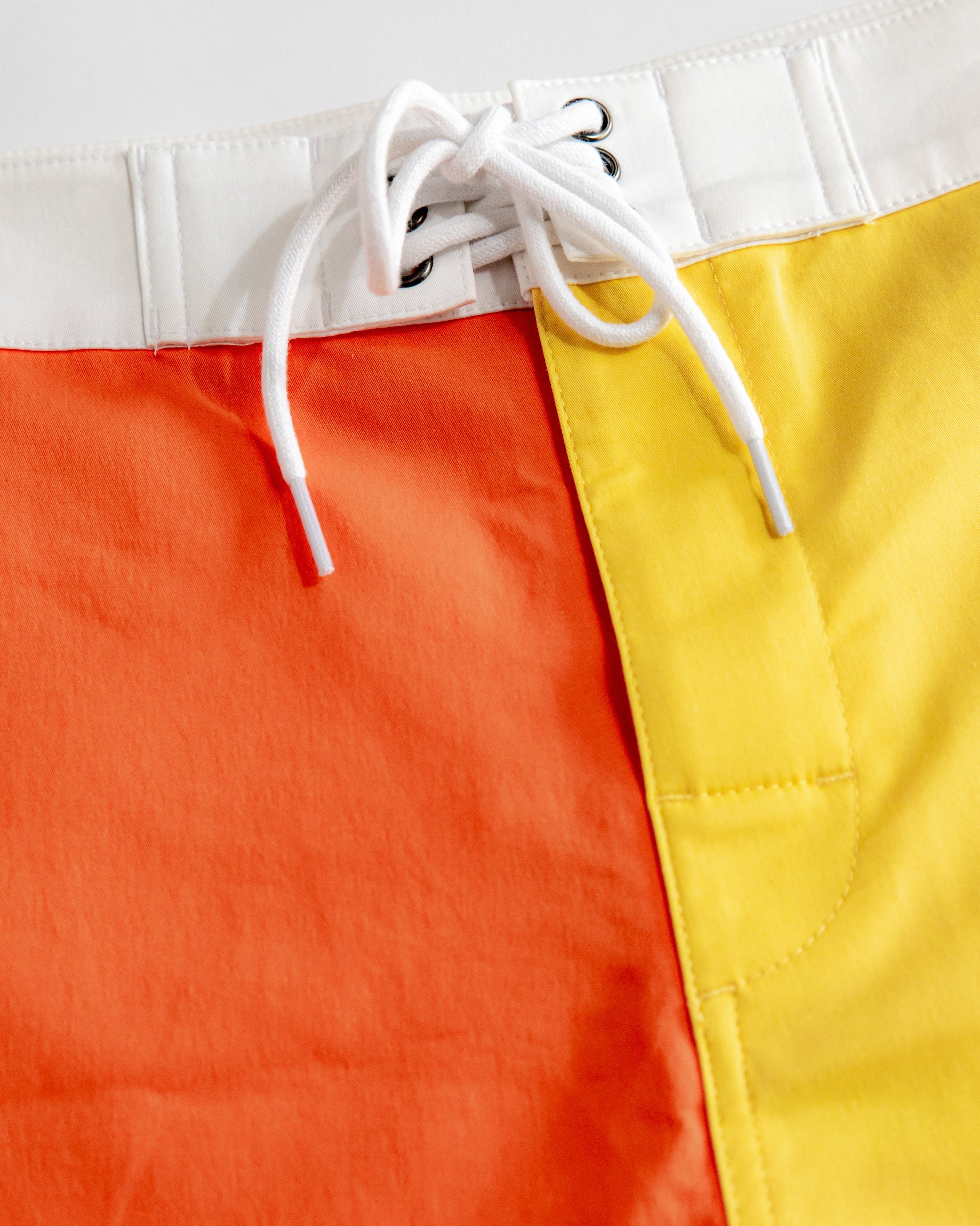 Color-blocked shorts with red, yellow, and white sections on a light gray background
