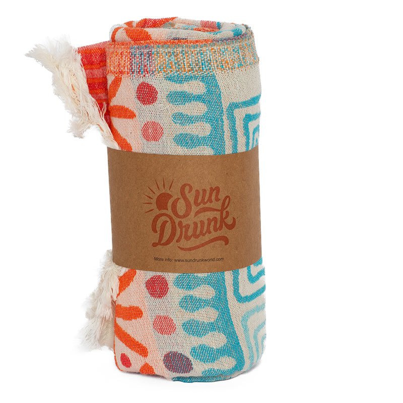 Colorful towel with abstract patterns and 'Sun Drunk' branding on a white background