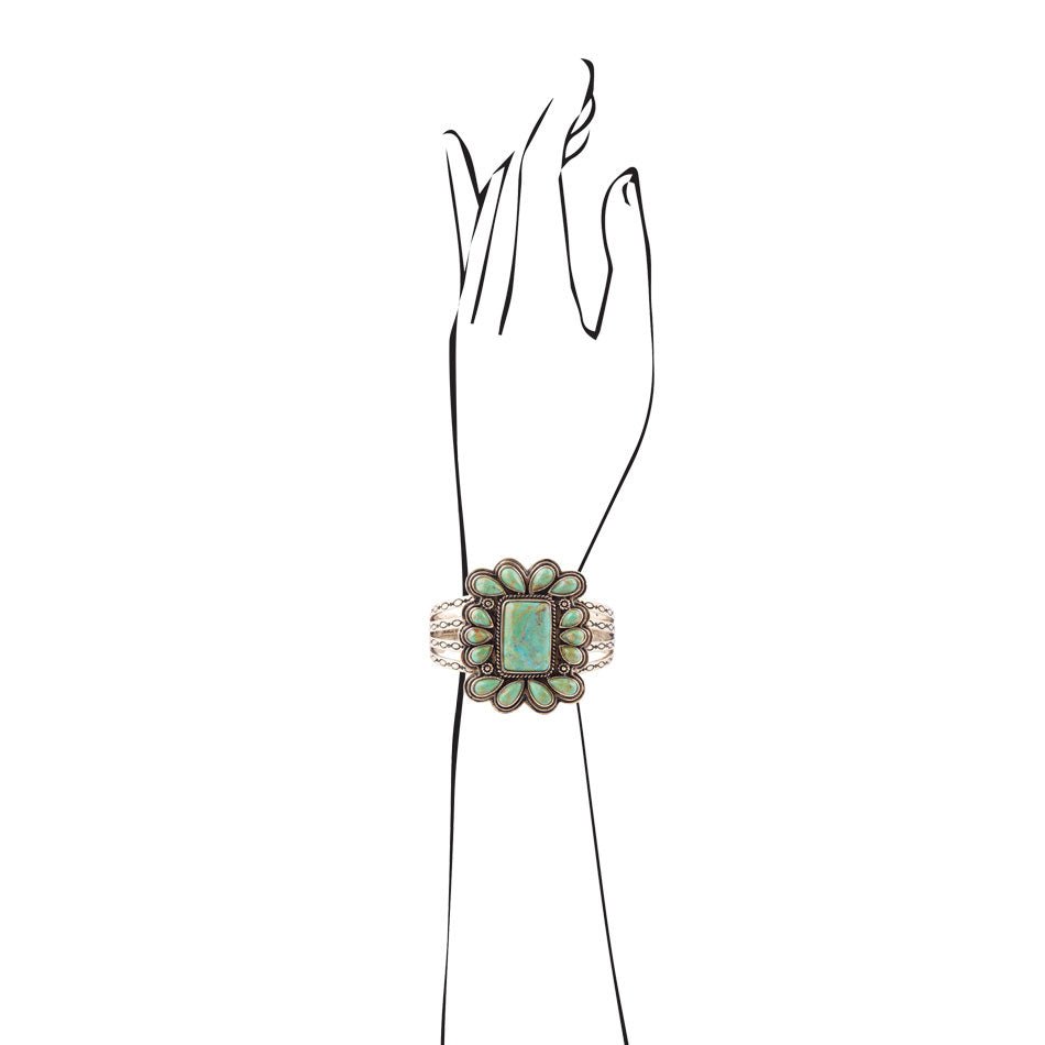 Decorative ring with a green gemstone on a black hand model against a white background