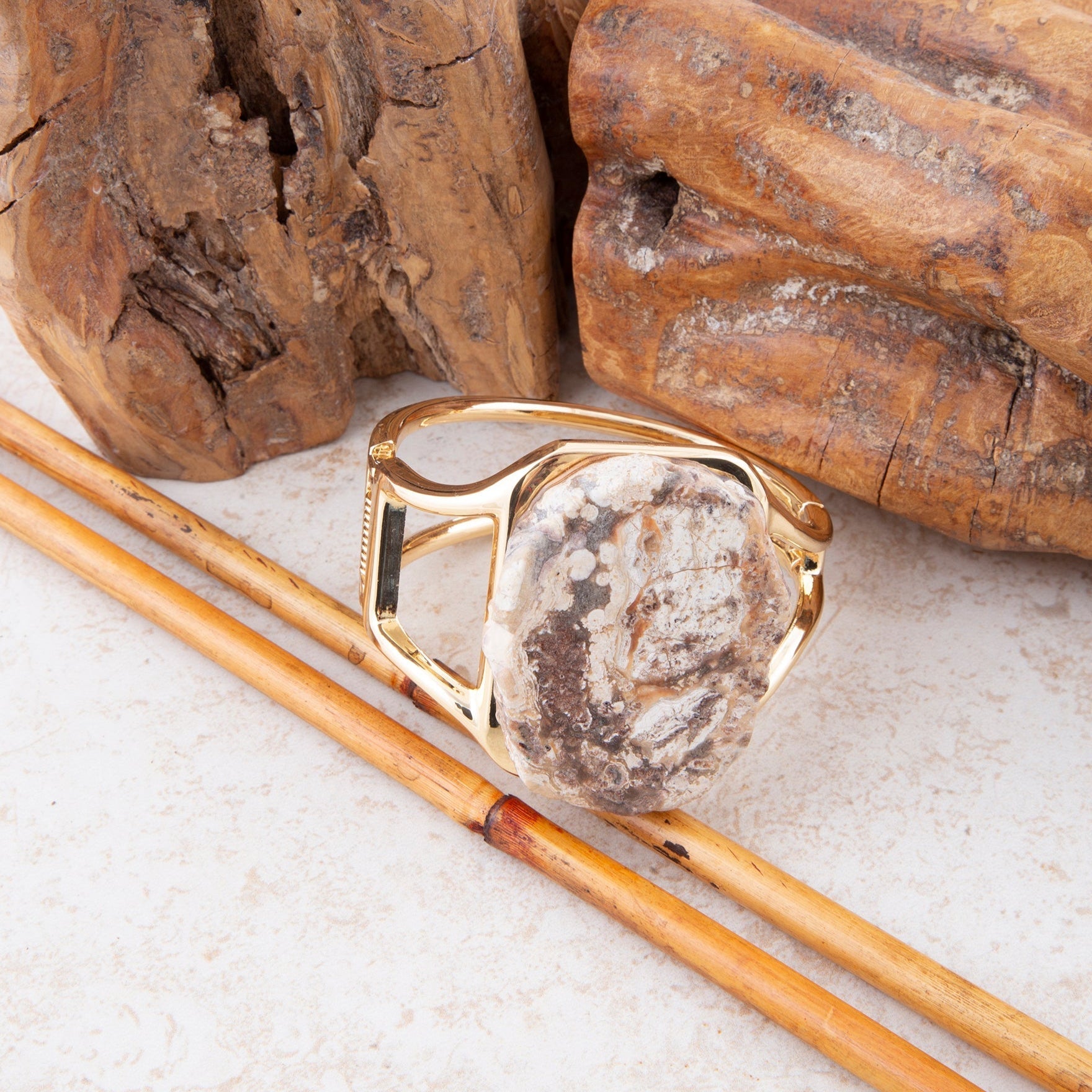 Gold ring with a stone inlay on a textured surface with wooden elements
