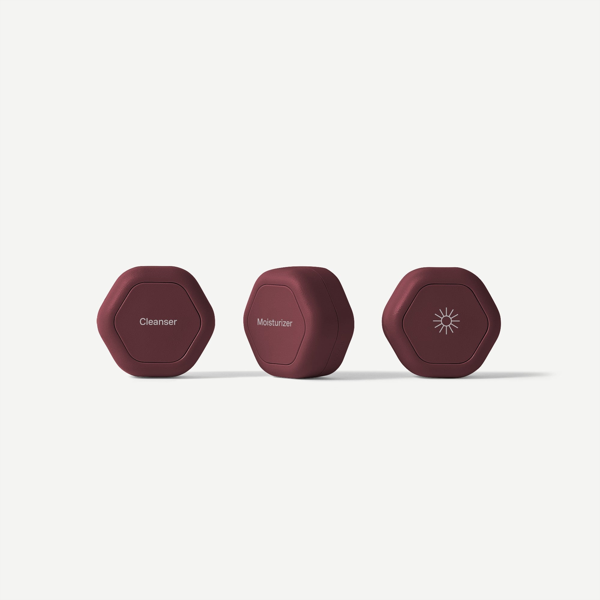 Three maroon cosmetic containers labeled 'Cleanser', 'Moisturizer', and 'Sunscreen' on a white background.
