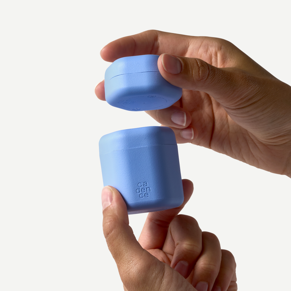Two blue containers held by a hand against a white background