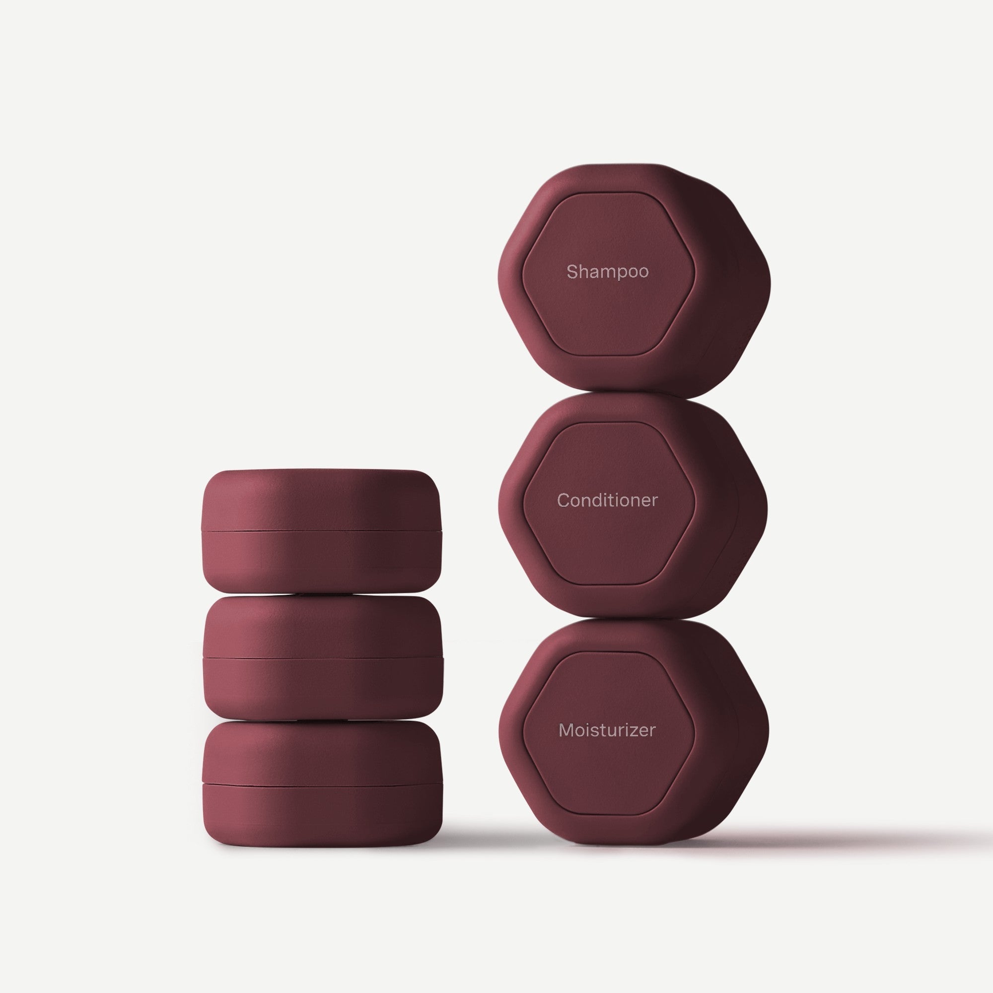 Set of four maroon containers labeled 'Shampoo', 'Conditioner', 'Moisturizer' on a light gray background