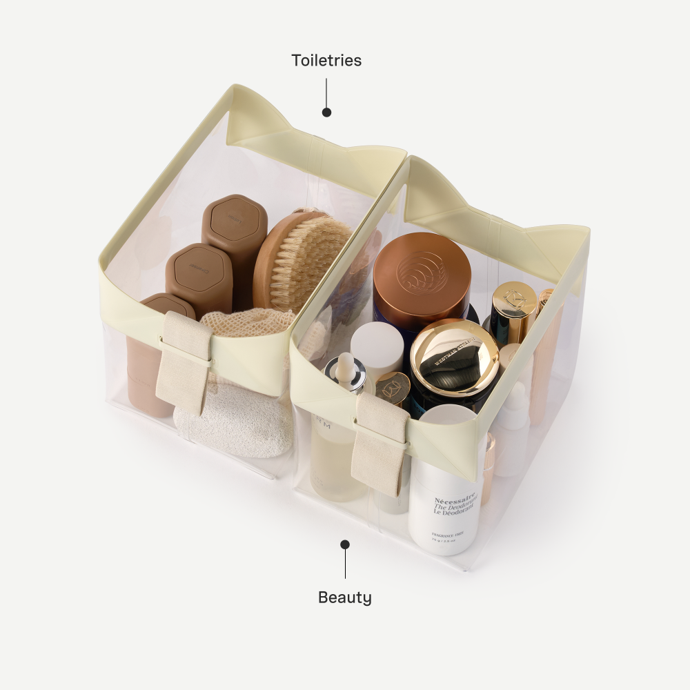 Clear storage basket with toiletries and beauty products on a white background