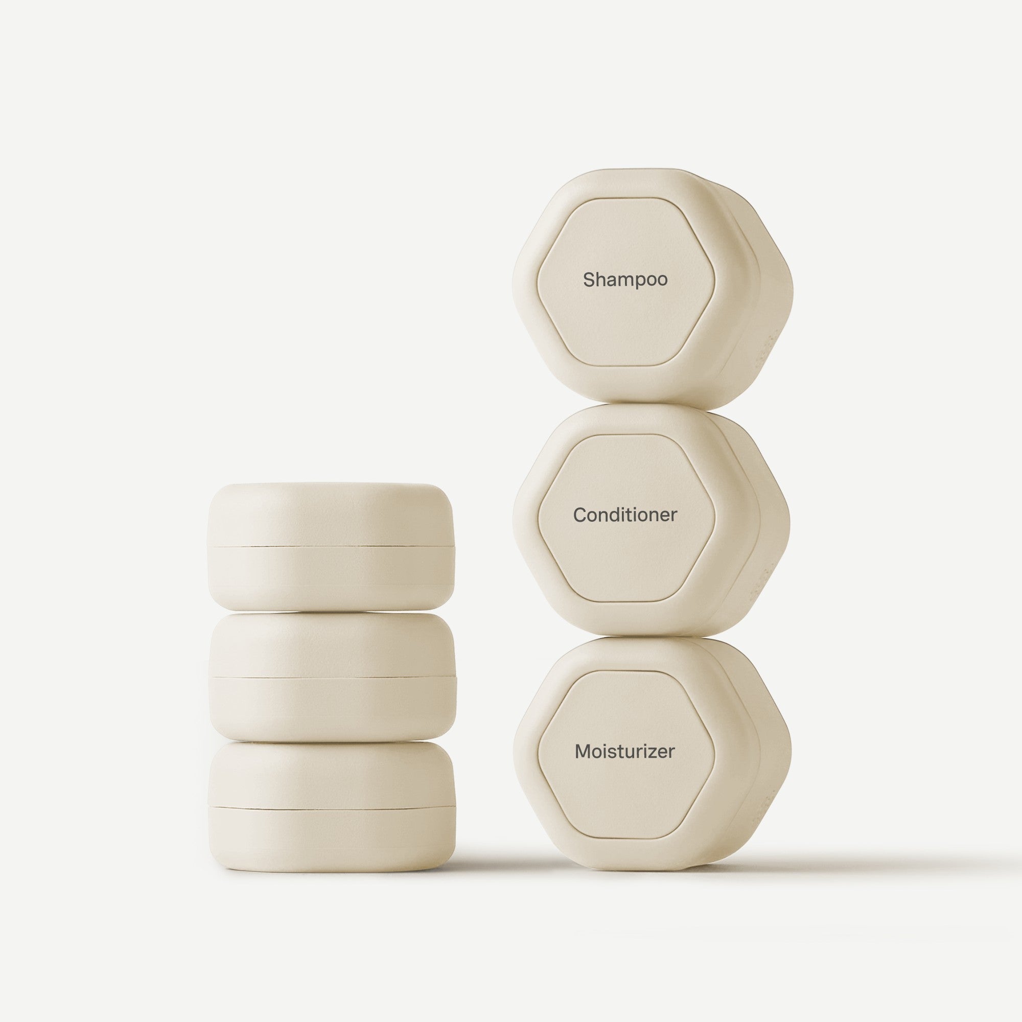Stack of beige hexagonal containers labeled 'Shampoo', 'Conditioner', and 'Moisturizer' on a white background