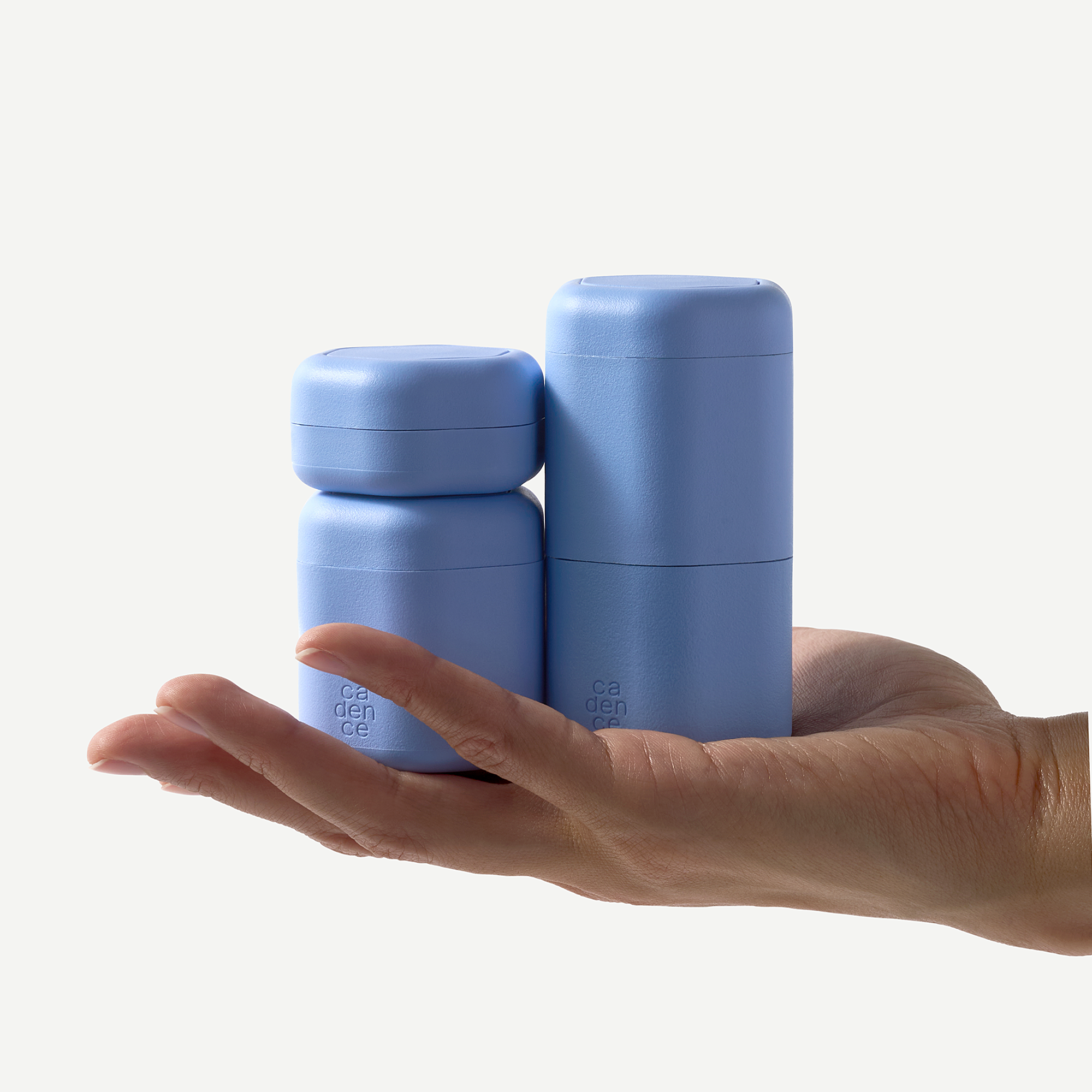 Two blue containers held in a hand against a white background