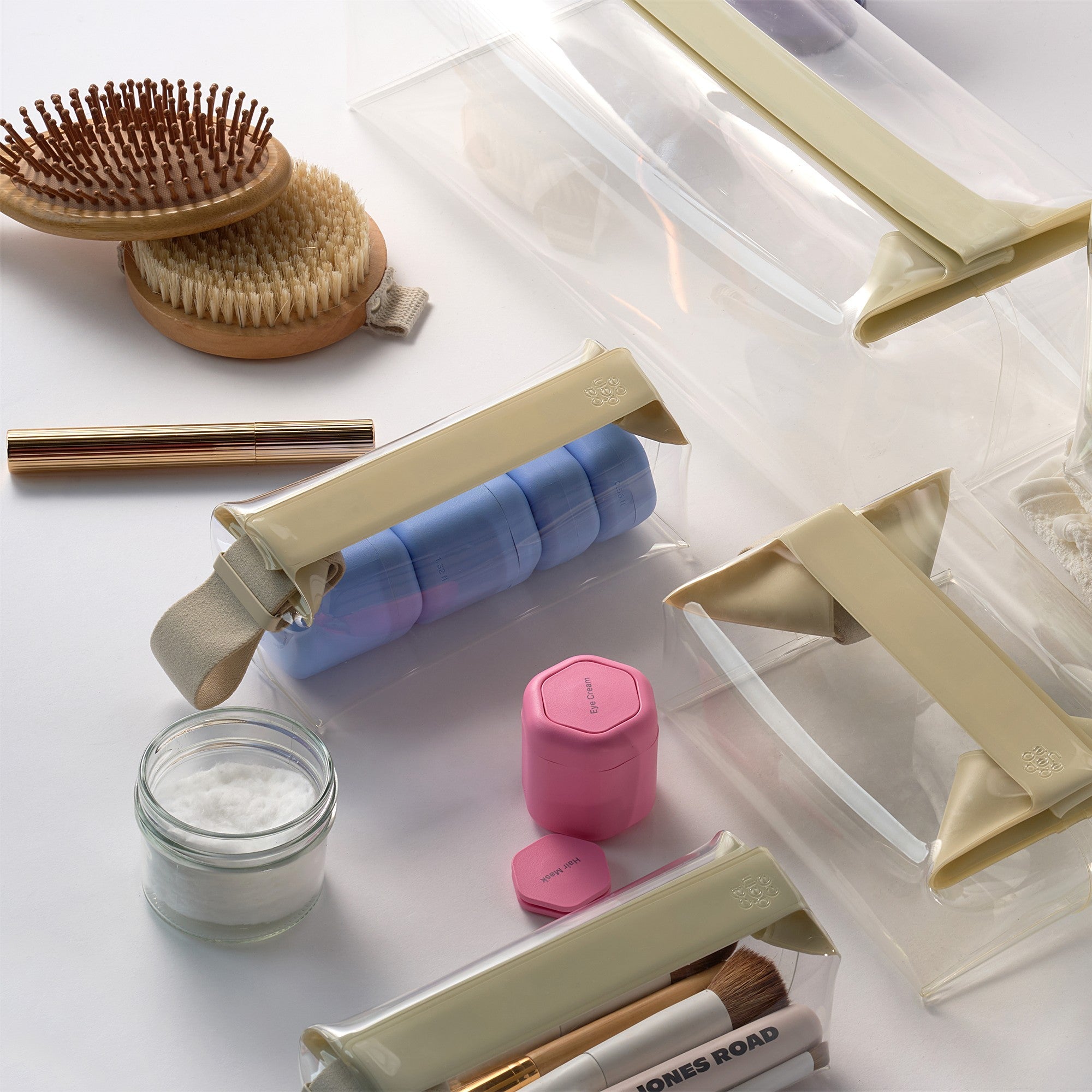 Collection of beauty products including a hairbrush, bottles, and containers on a white surface.