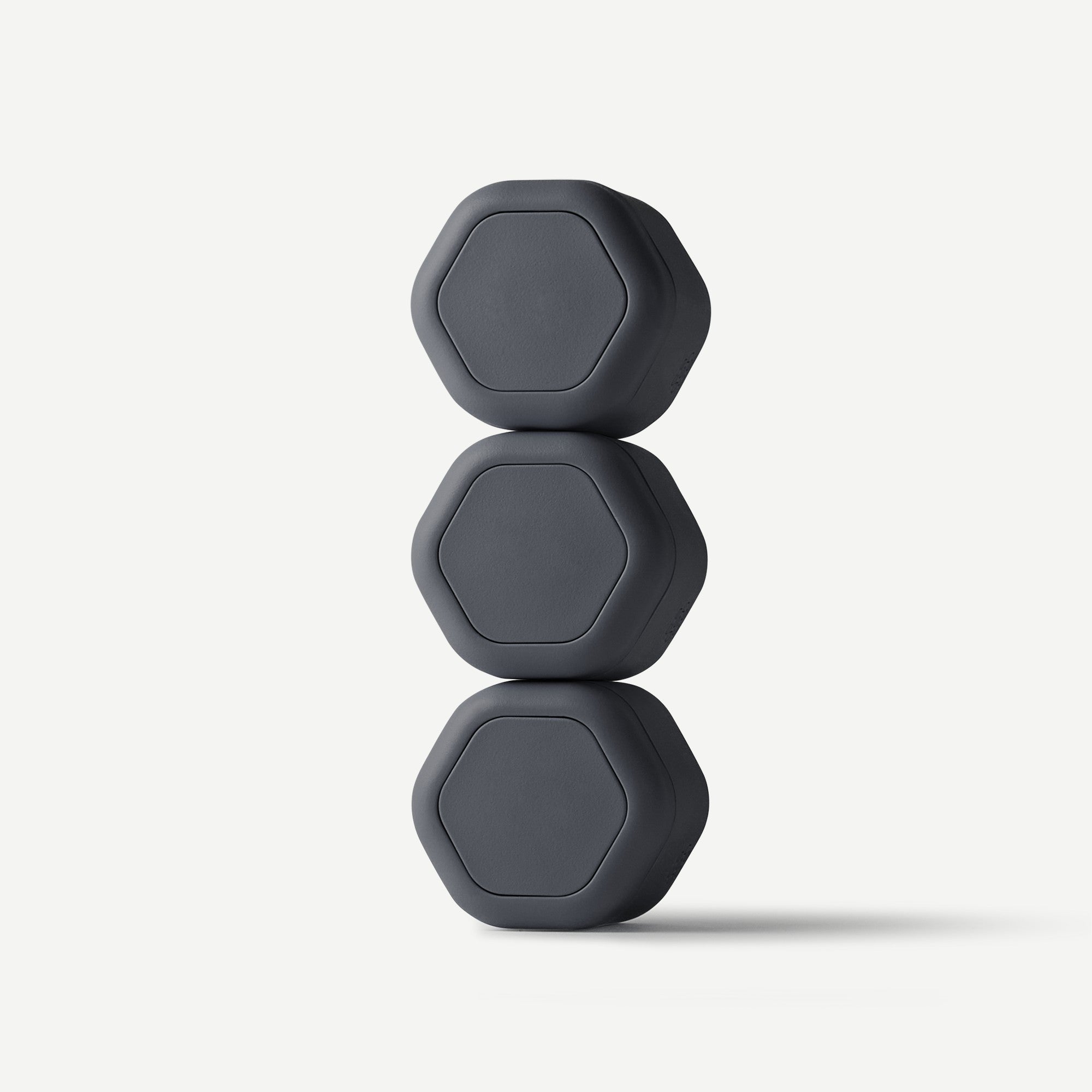 Three dark gray hexagonal portable speakers stacked vertically on a light gray background.