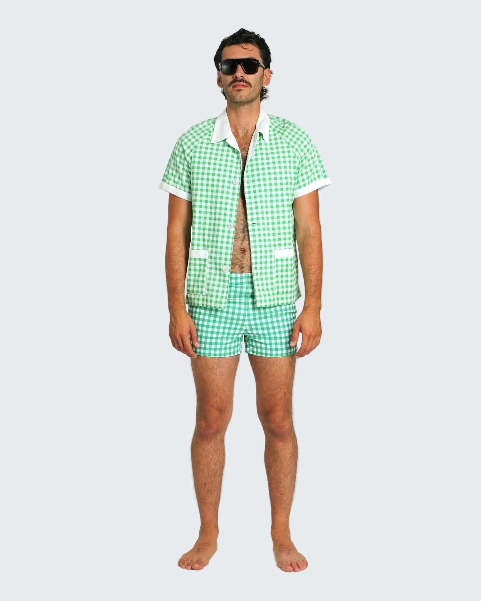 Man wearing a green checkered shirt and shorts set on a white background