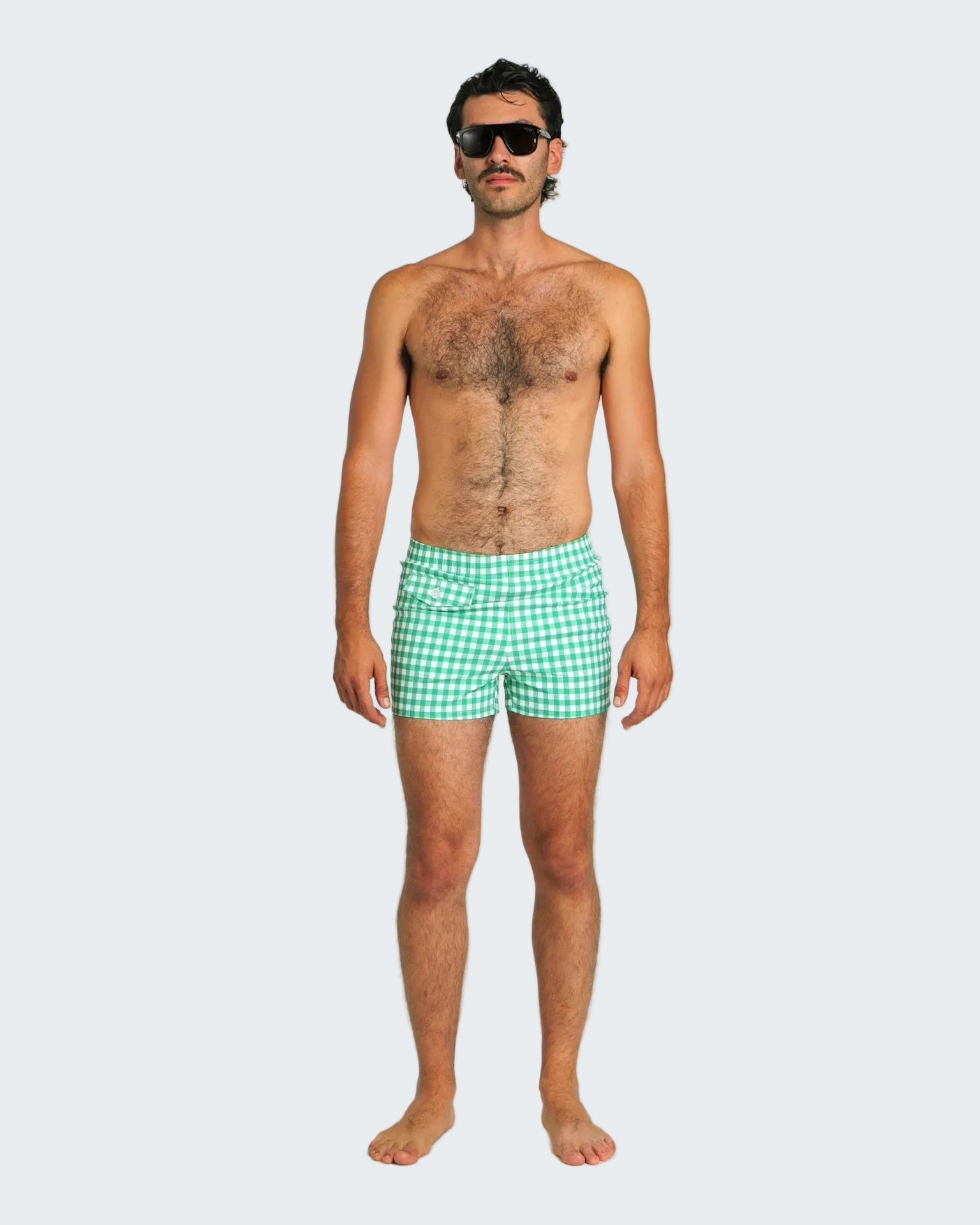 Man wearing green checkered swim shorts on a white background