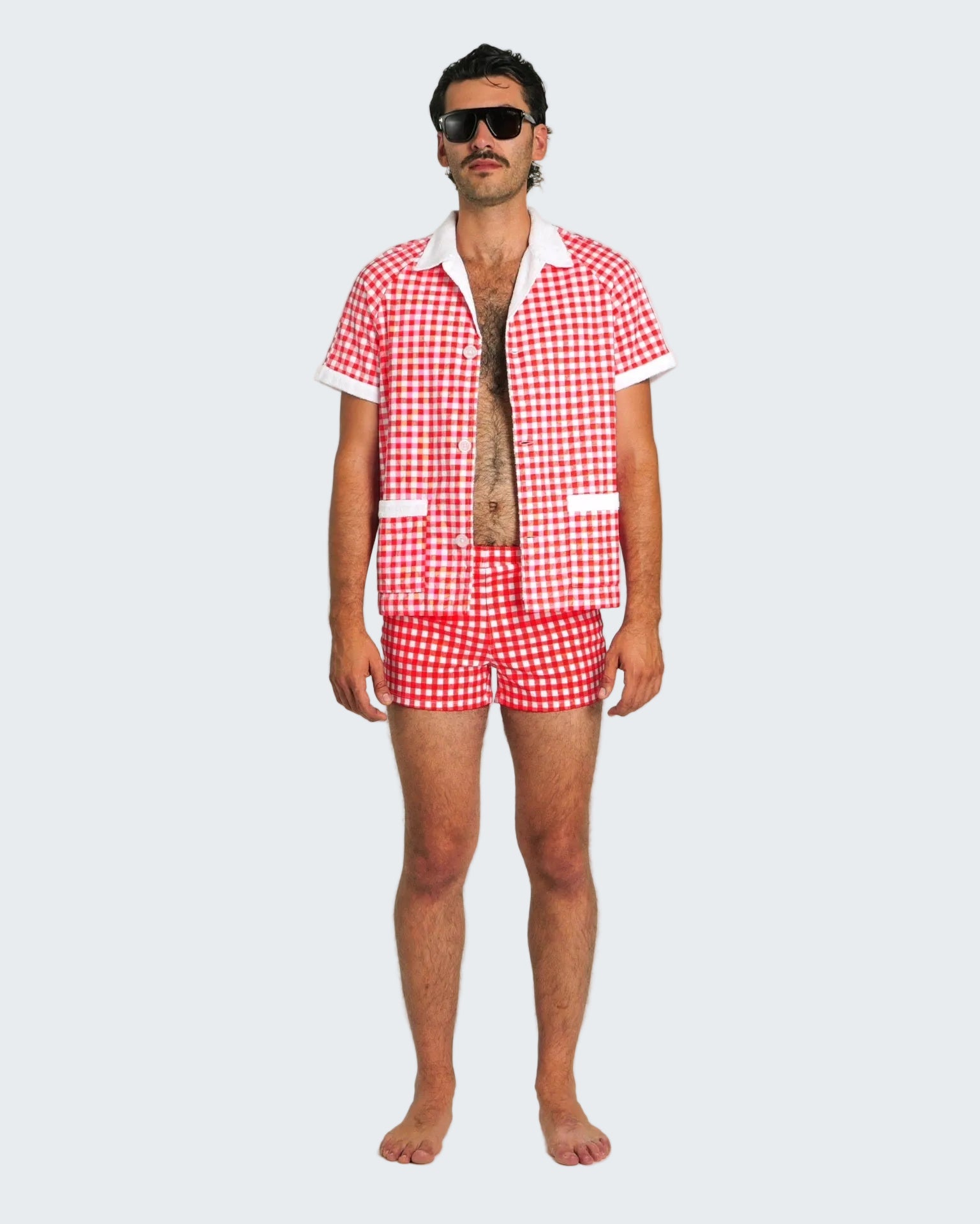 Man wearing a red and white checkered shirt and shorts on a white background