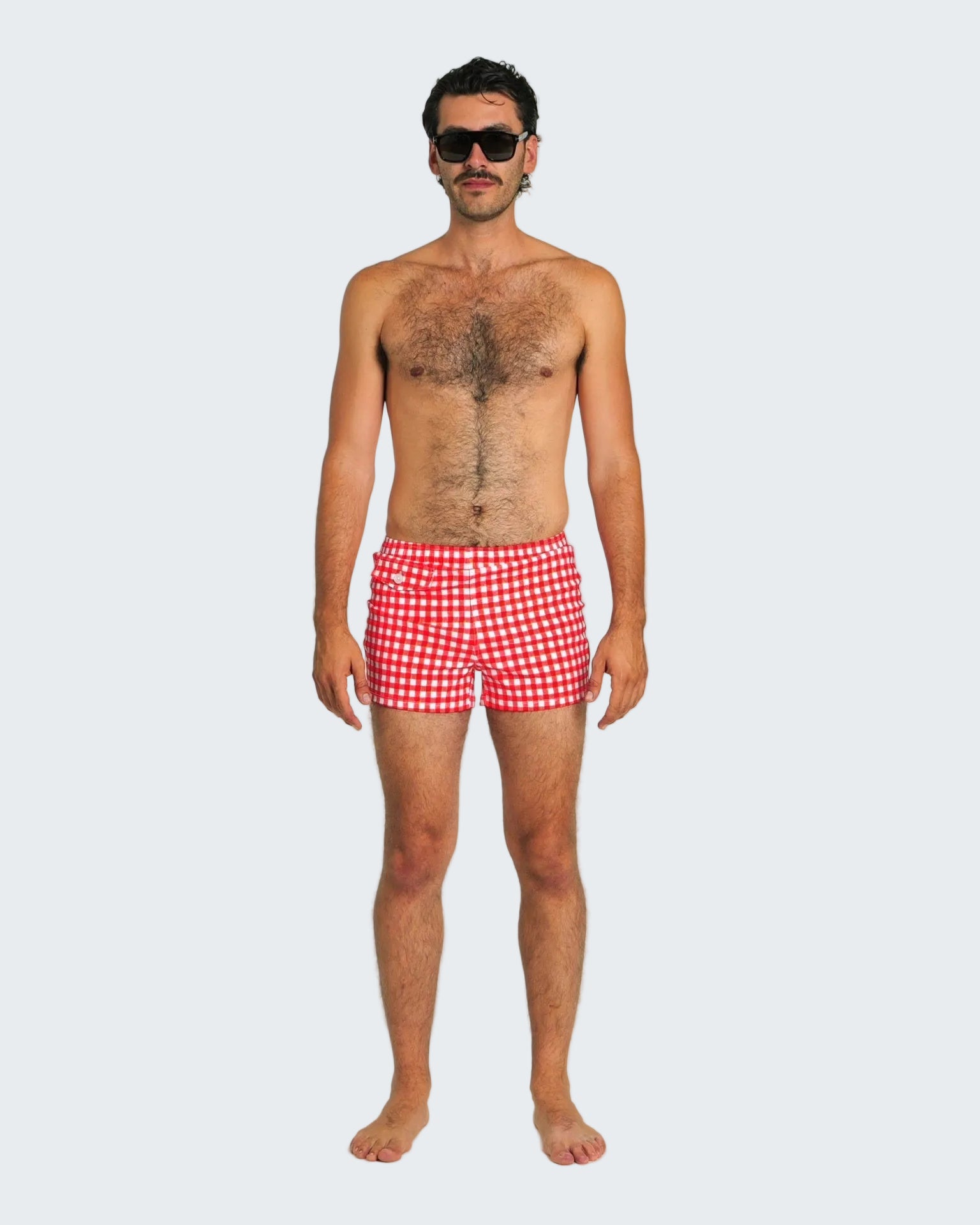 Man wearing red checkered swim shorts on a white background