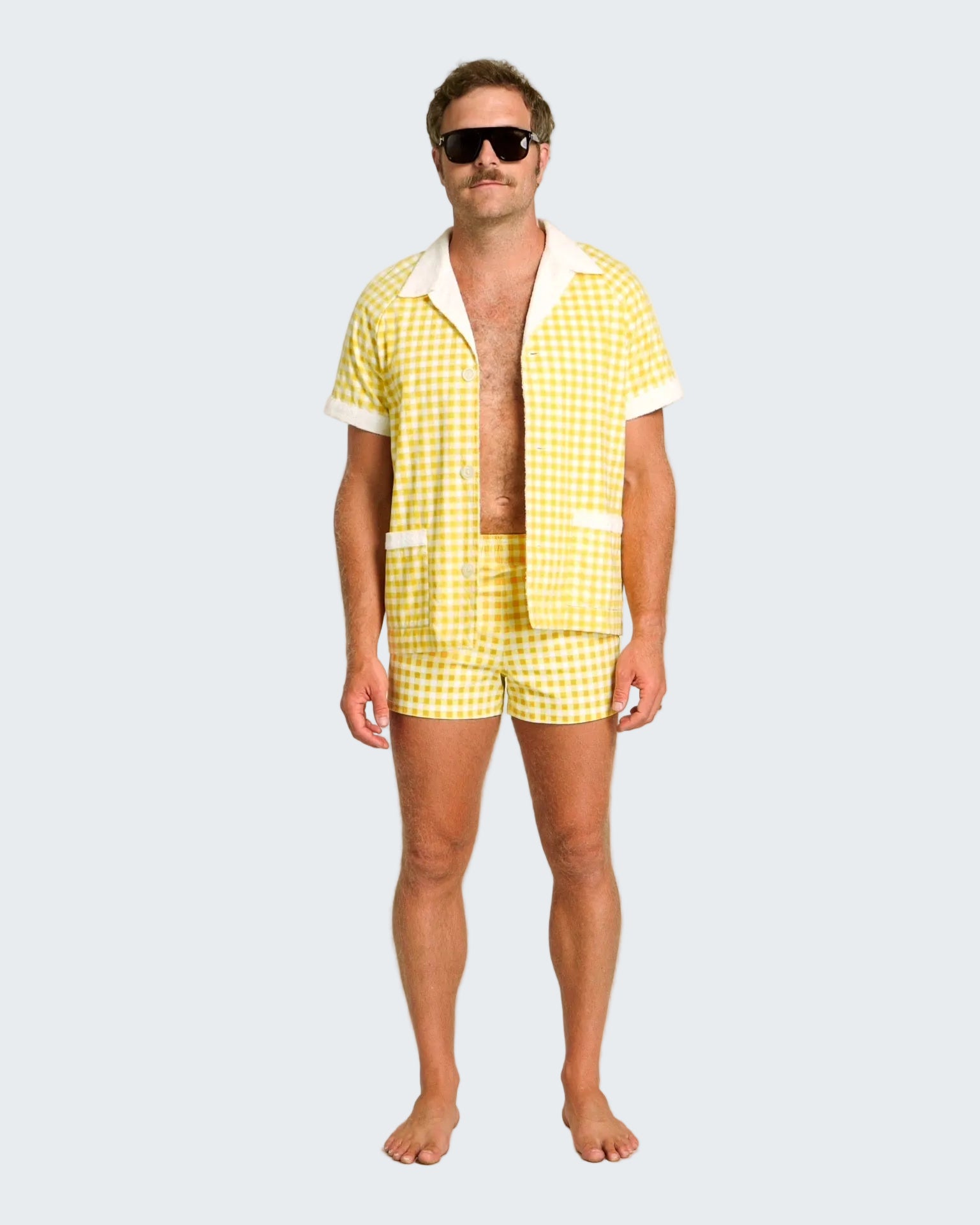 Man wearing a yellow checkered shirt and shorts set on a white background
