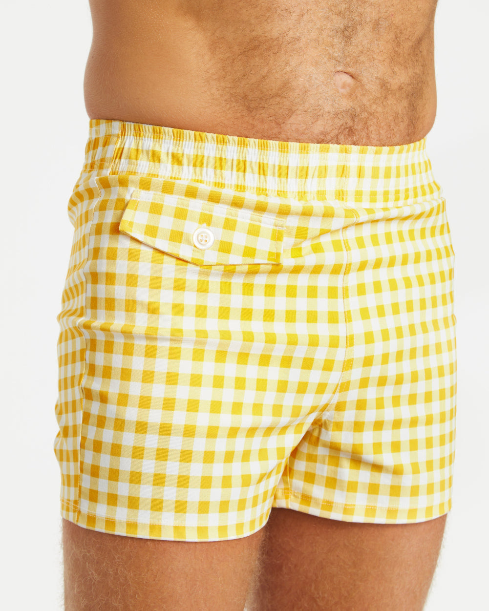 Yellow and white checkered shorts worn by a person on a light gray background