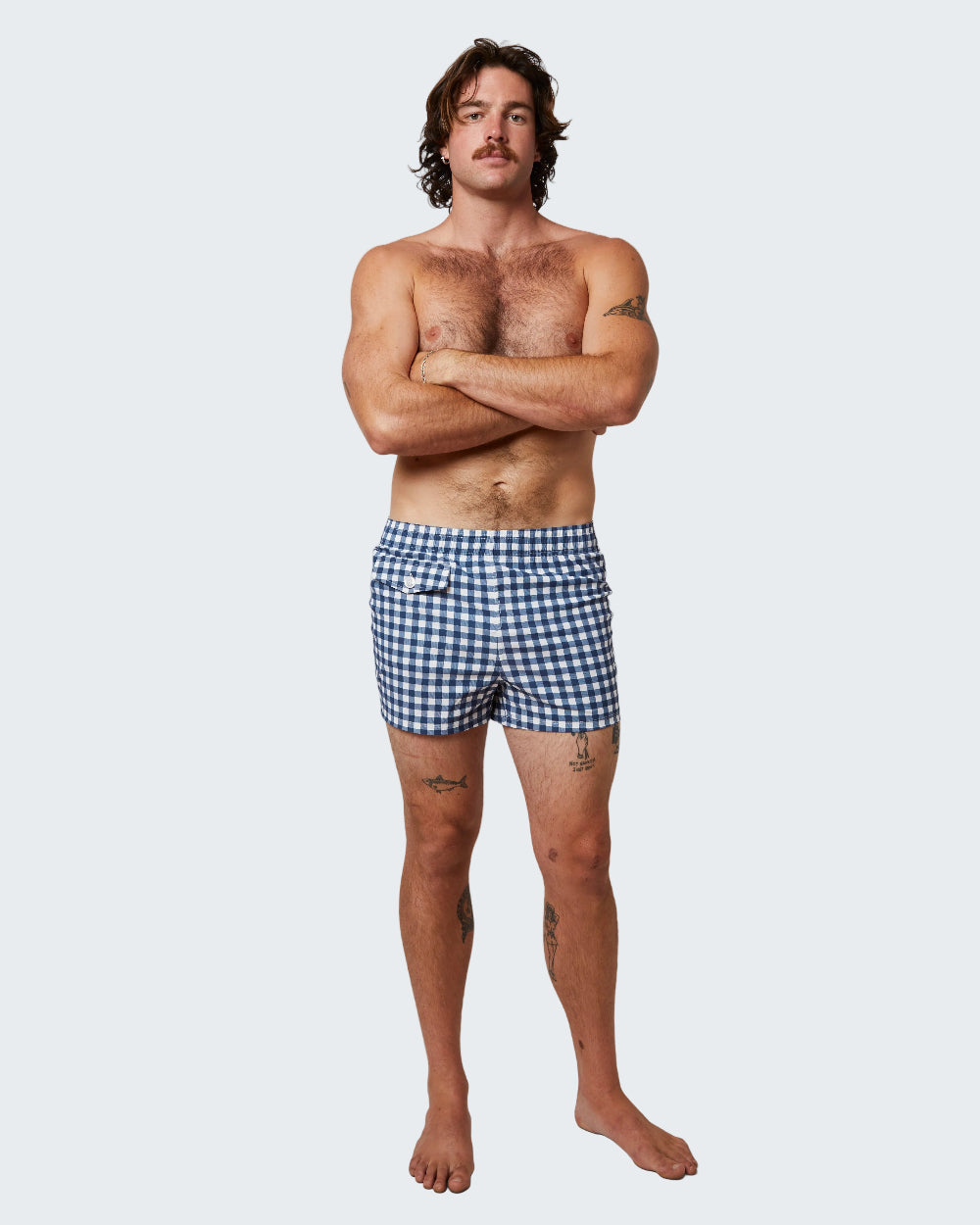 Man wearing blue checkered swim shorts on a white background