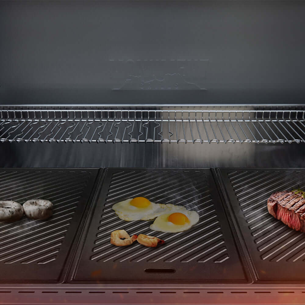 Grill with food items including eggs, shrimp, and a steak on a dark background