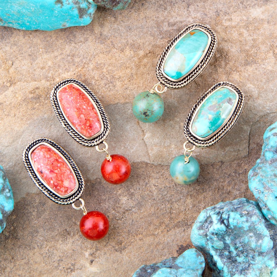Pair of earrings with turquoise and coral stones on a stone surface